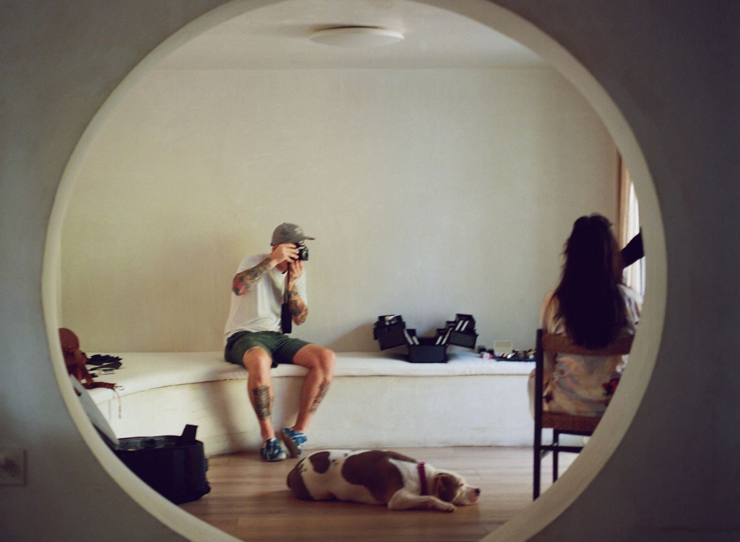 Sequence of images through an oval frame showing movement in a minimalist white room.