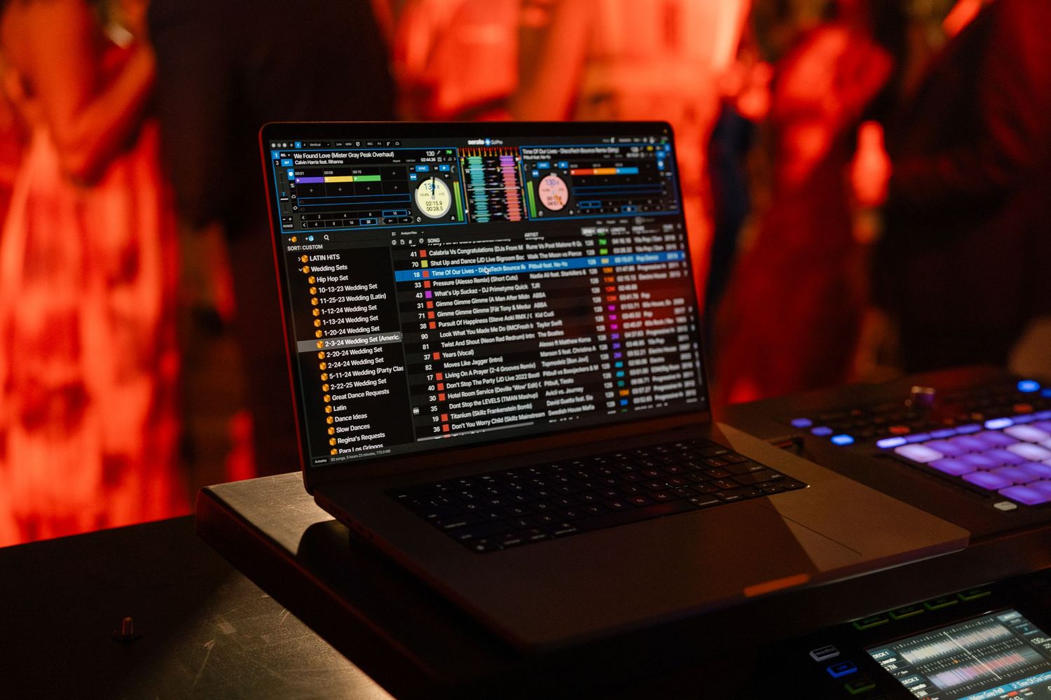 DJ software interface displayed on laptop screen with red ambient lighting.