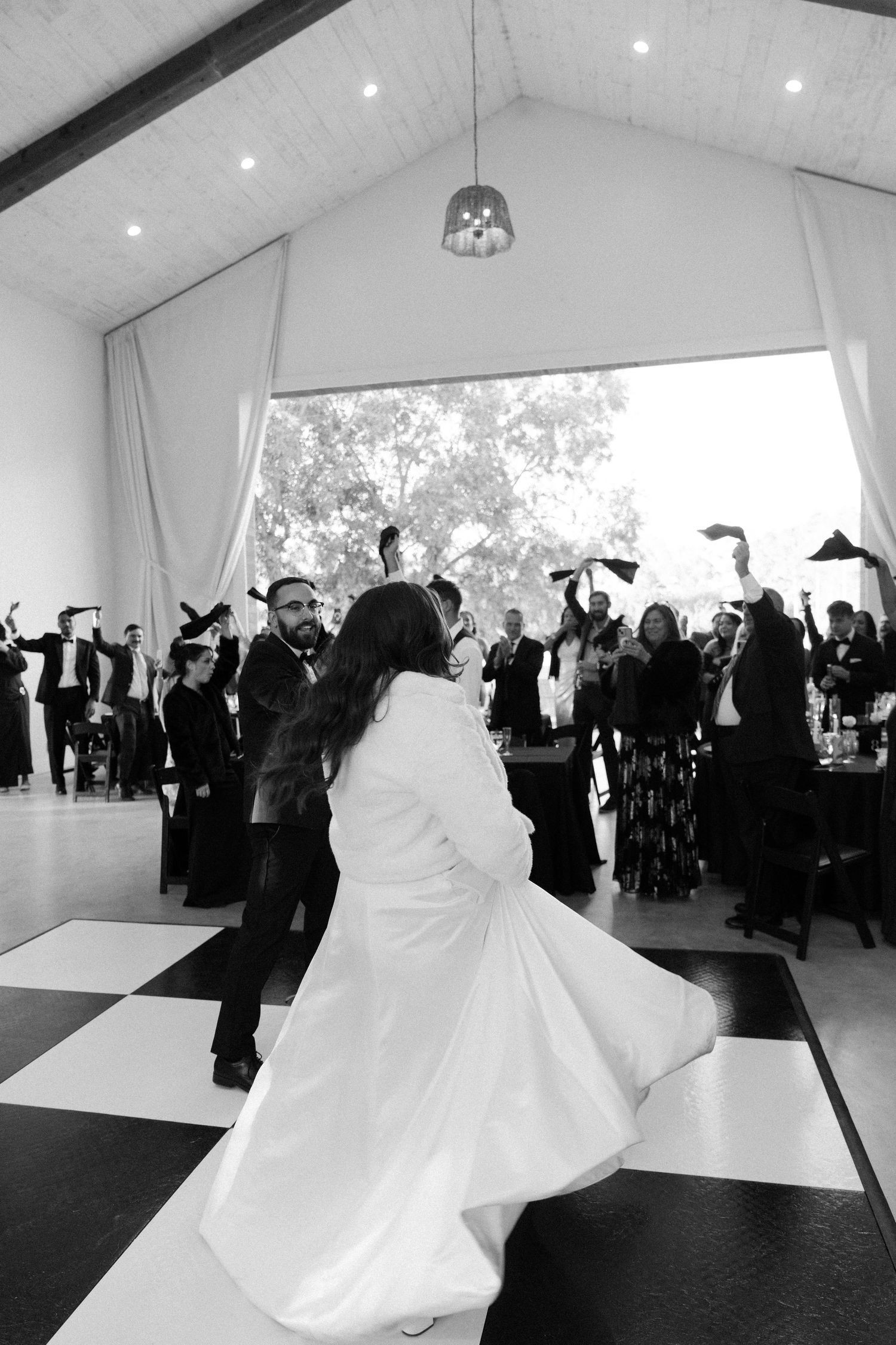 A bride in a white dress dancing with guests at a wedding reception.