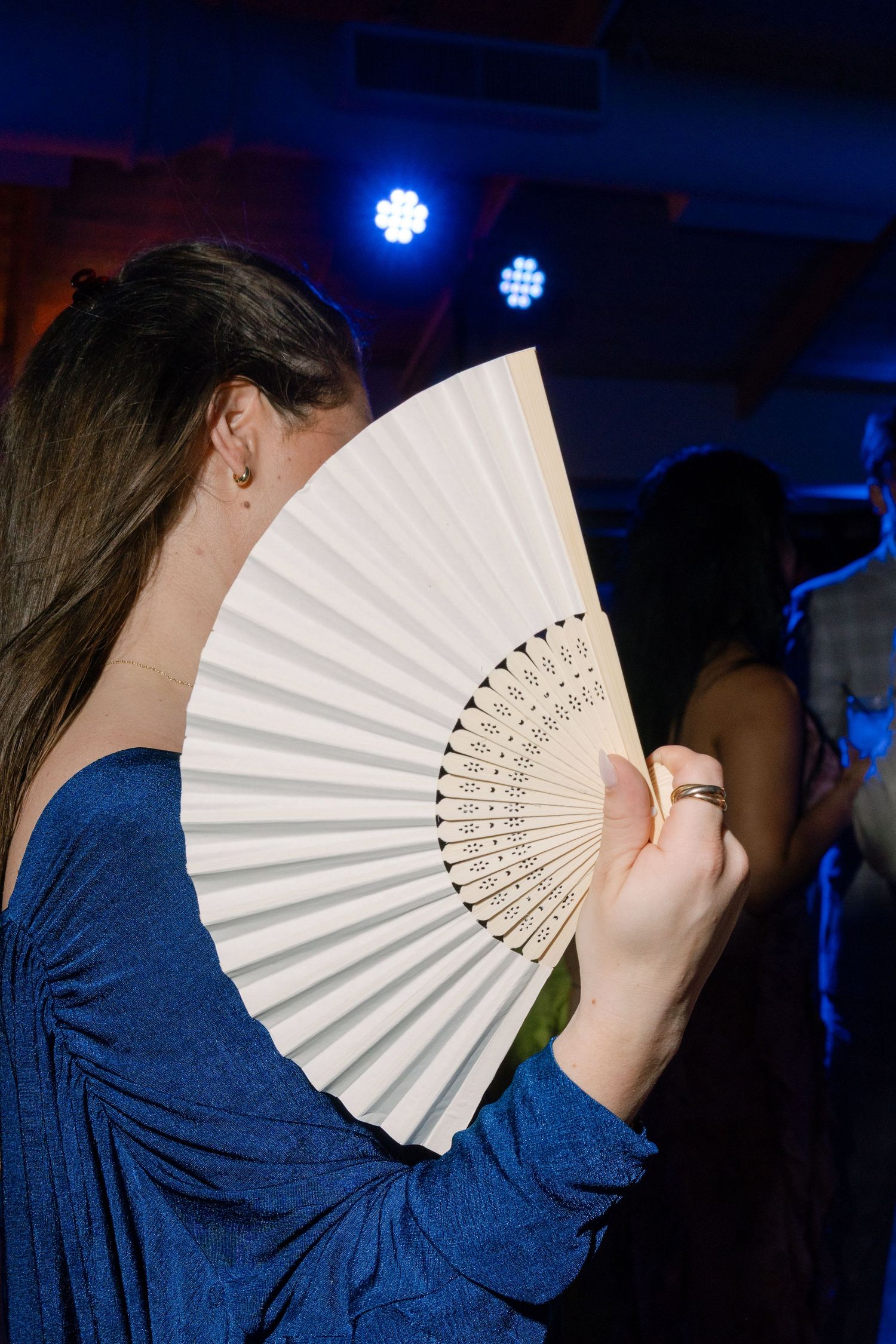 A sequence of photos shows someone in a blue shirt holding up a white folding fan in front of their face.
