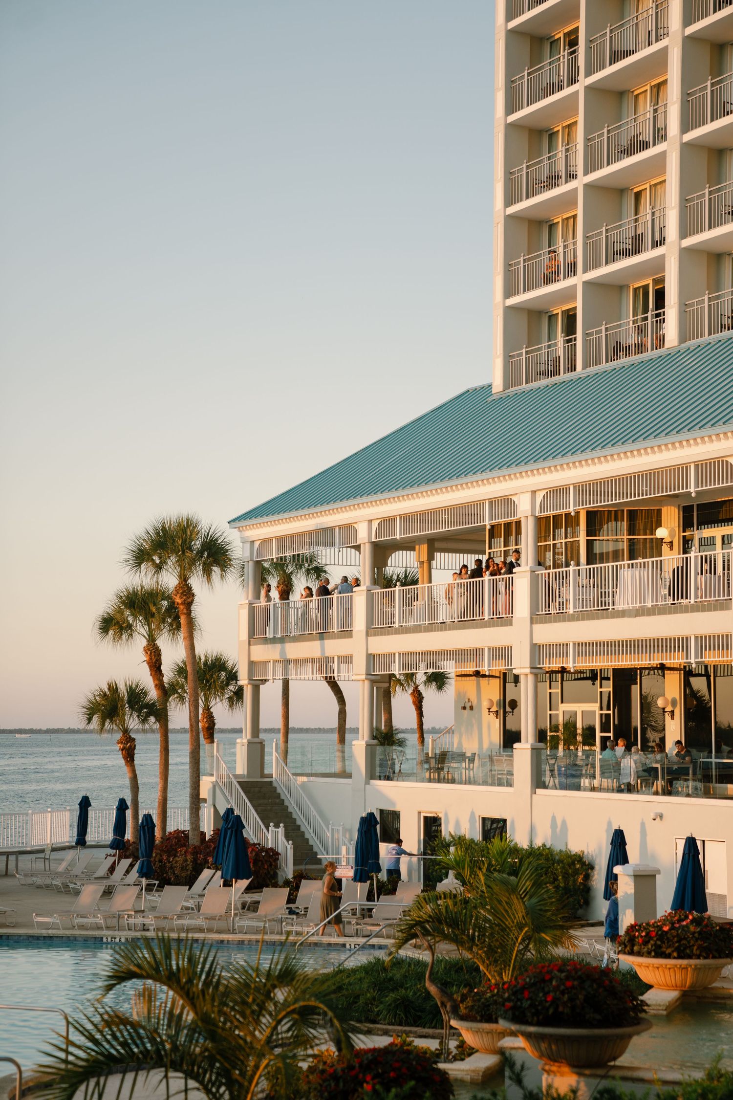 Beachfront hotel with palm trees and balconies at sunset.