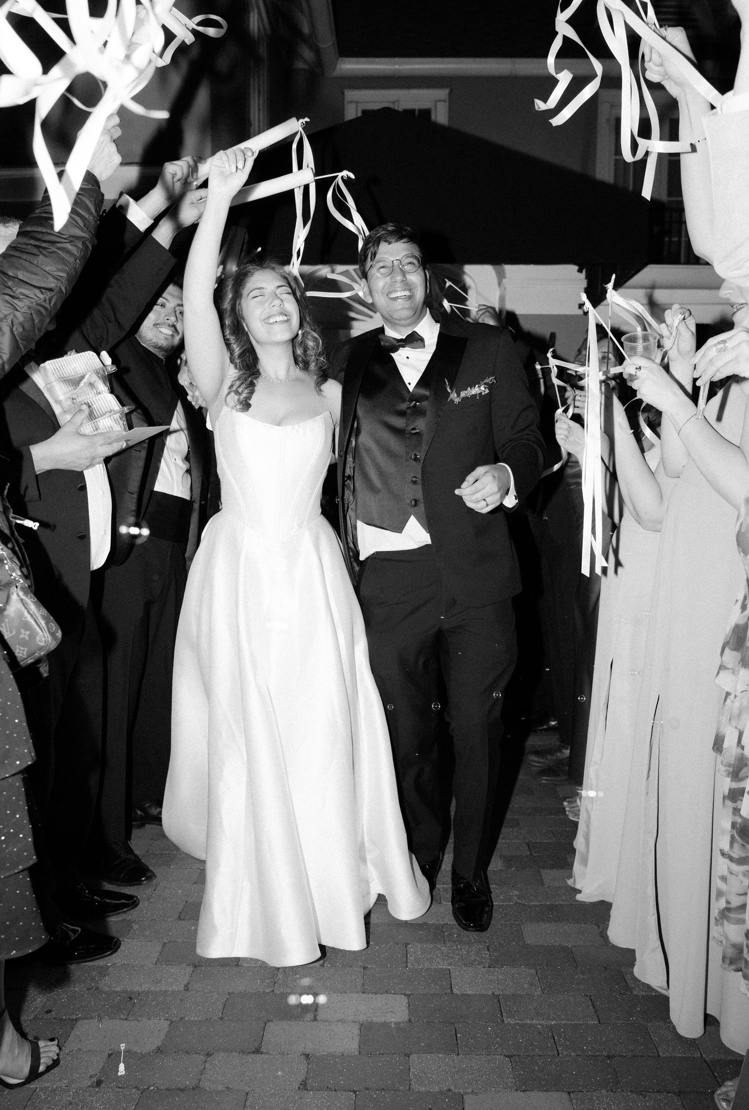 Wedding party celebrates at exit with guests holding sparklers in black and white photograph.