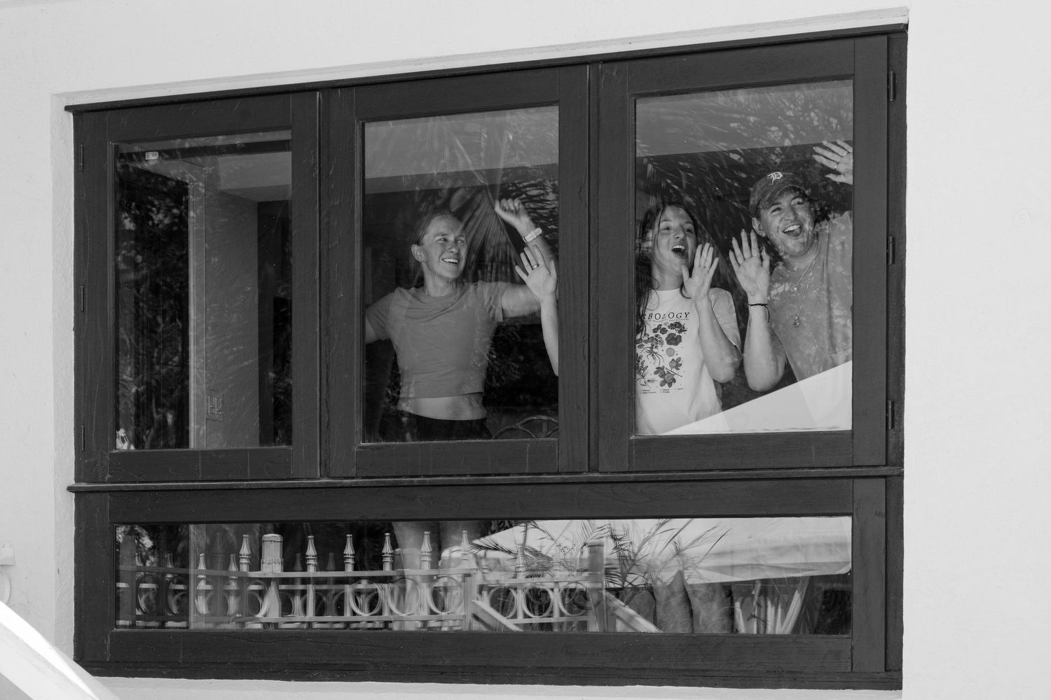Black and white image showing three people, likely women, posing in a window display.