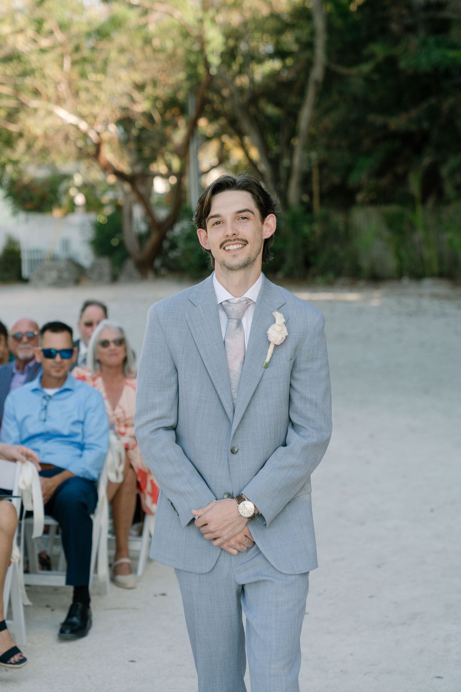 A bride and groom posing for a photograph in a tropical outdoor setting.
