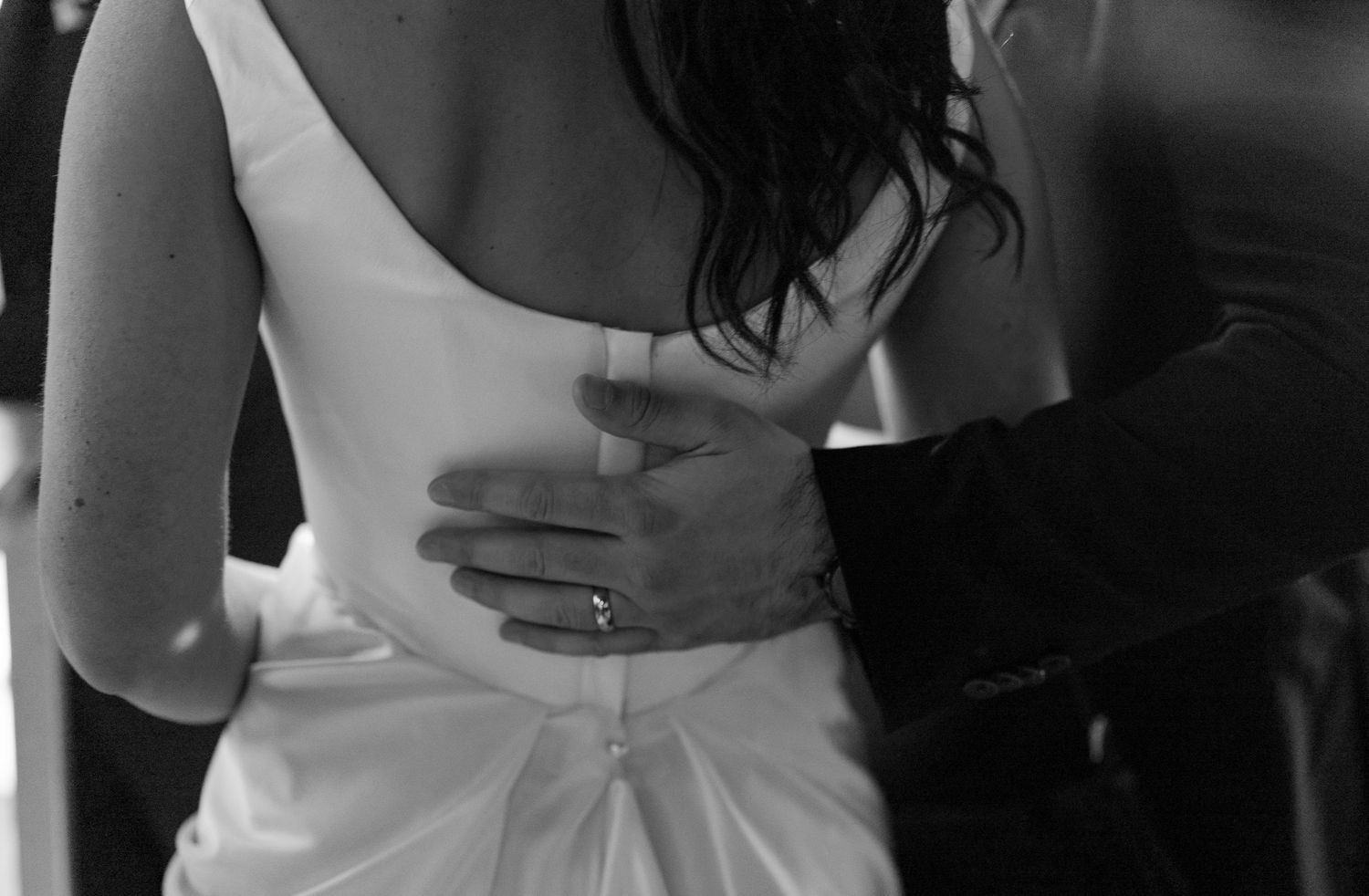 Artistic black and white detail shots of wedding attire and embraces.