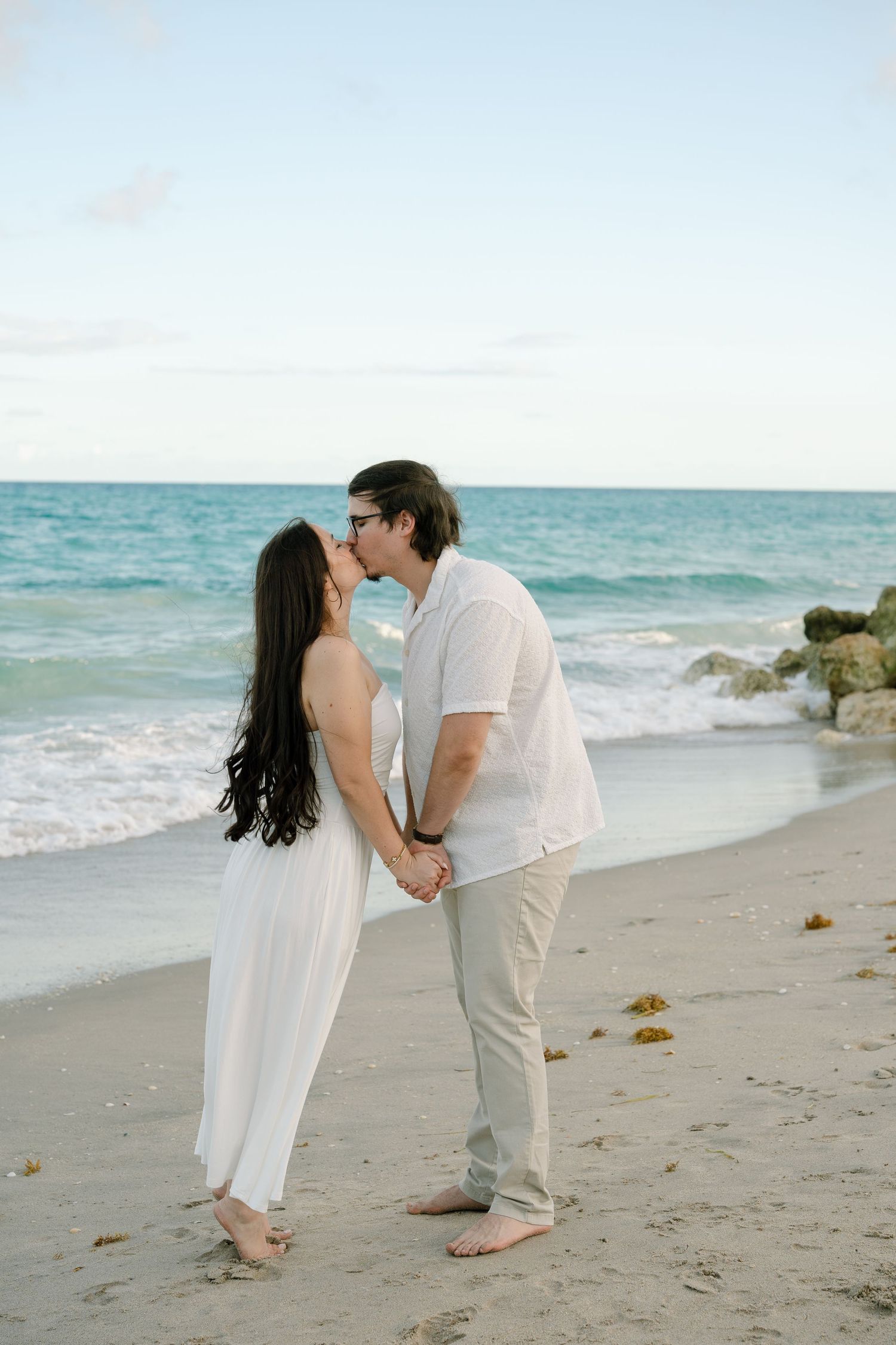 A couple shares an intimate moment on a beautiful beach with turquoise waters and white sand.