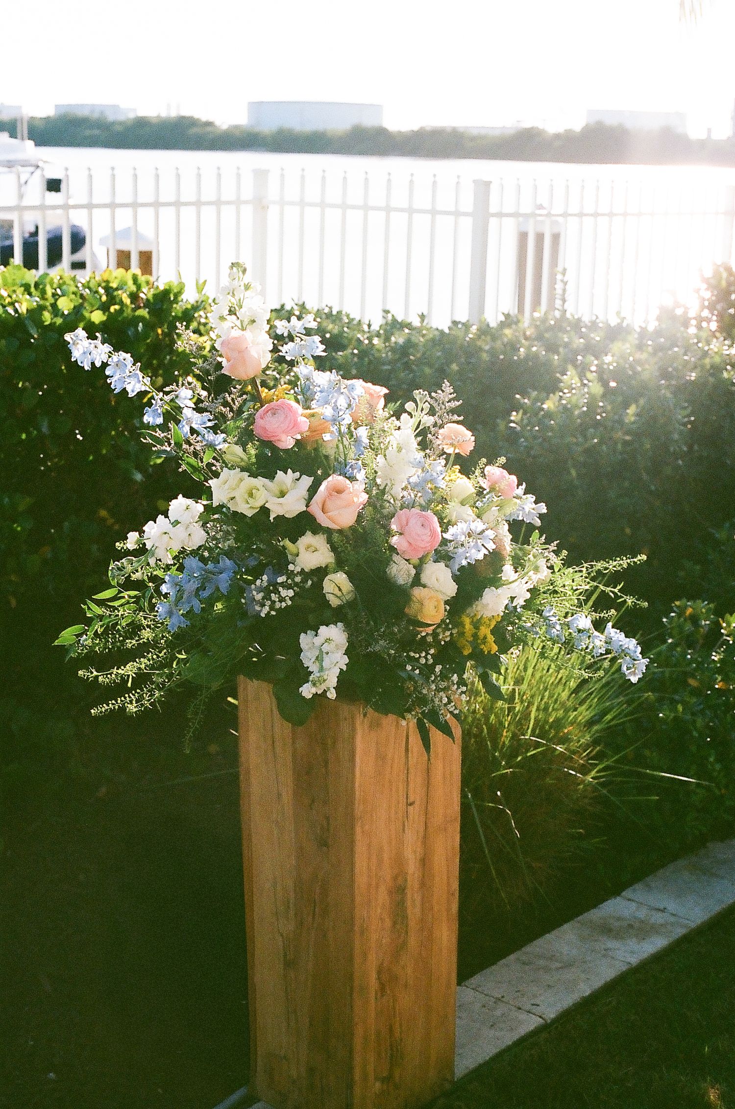 Rustic wooden planter box filled with pink and white flowers decorates an outdoor wedding venue.