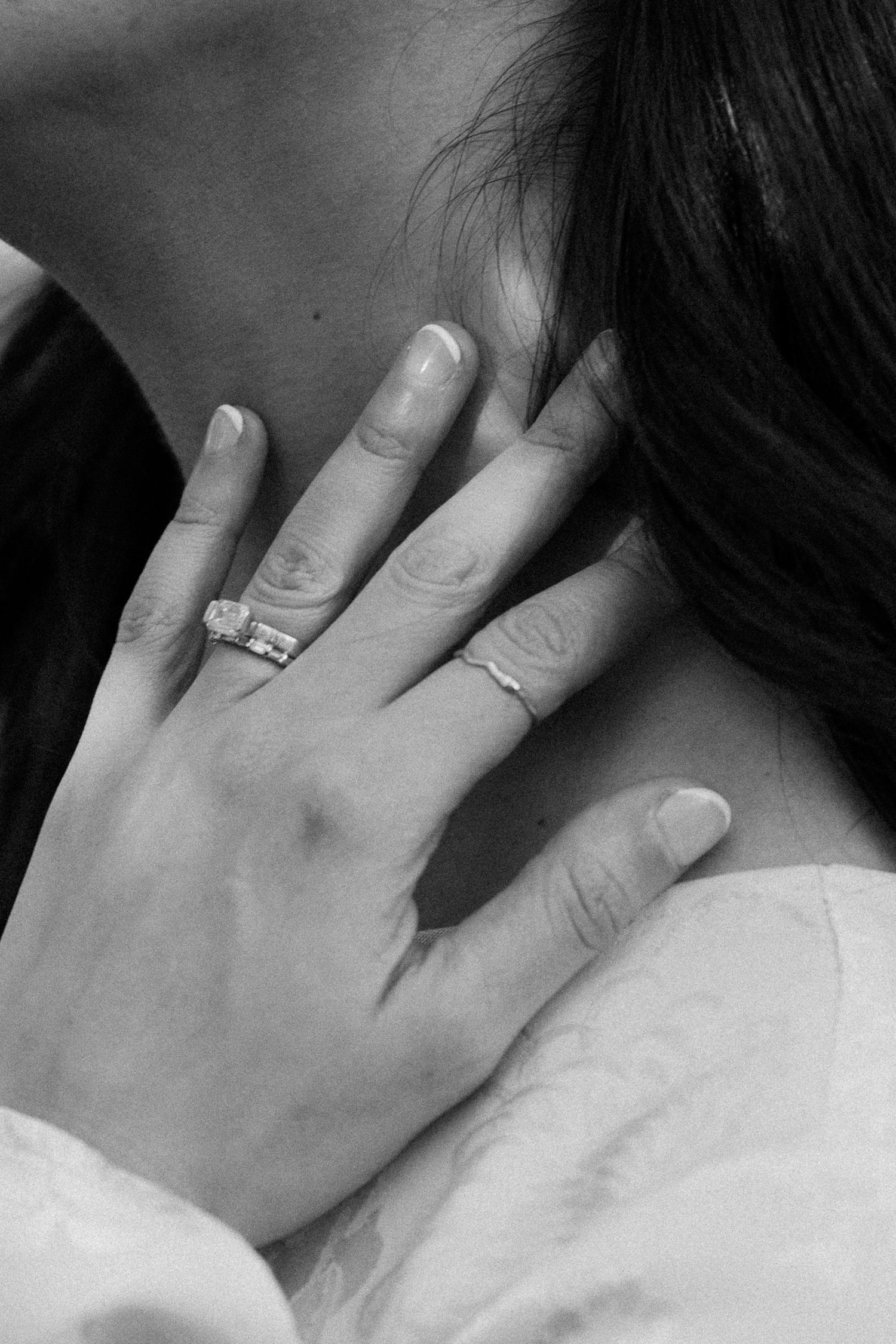 Close-up of hands with engagement ring and wedding band in black and white.