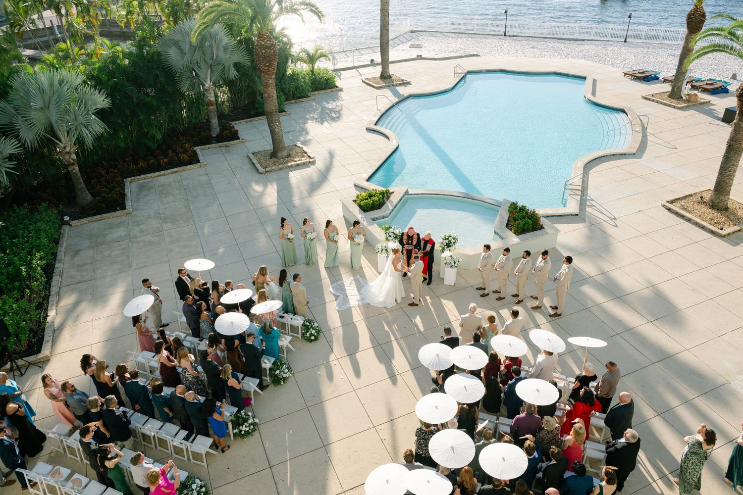 Aerial view of outdoor beach wedding ceremony setup with rows of white chairs and ocean backdrop.