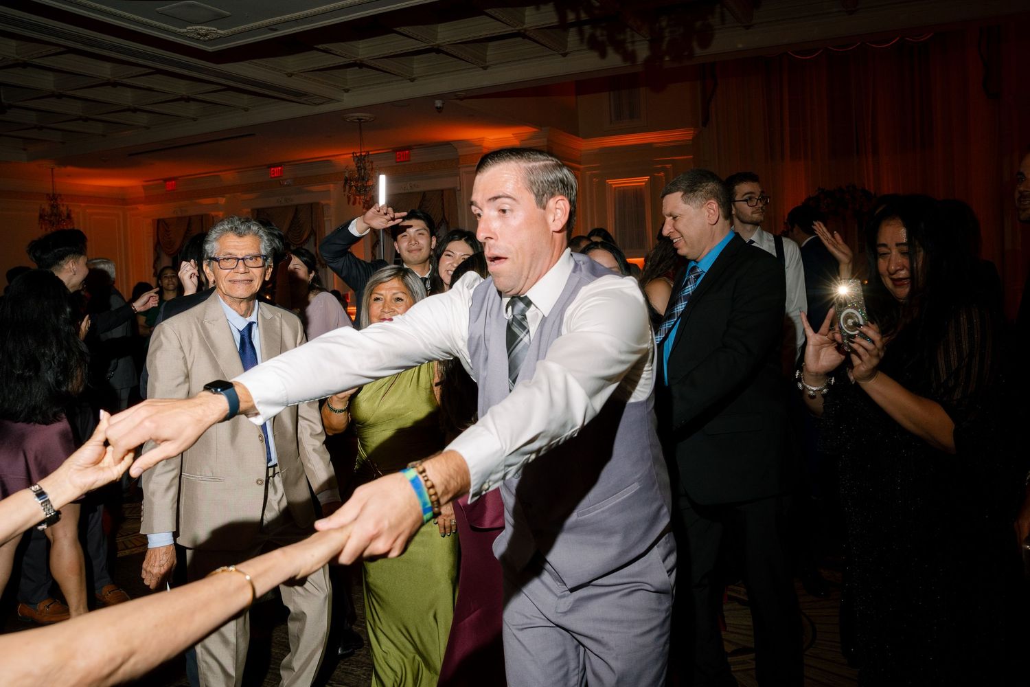 Wedding guests forming a dance line during reception celebrations.