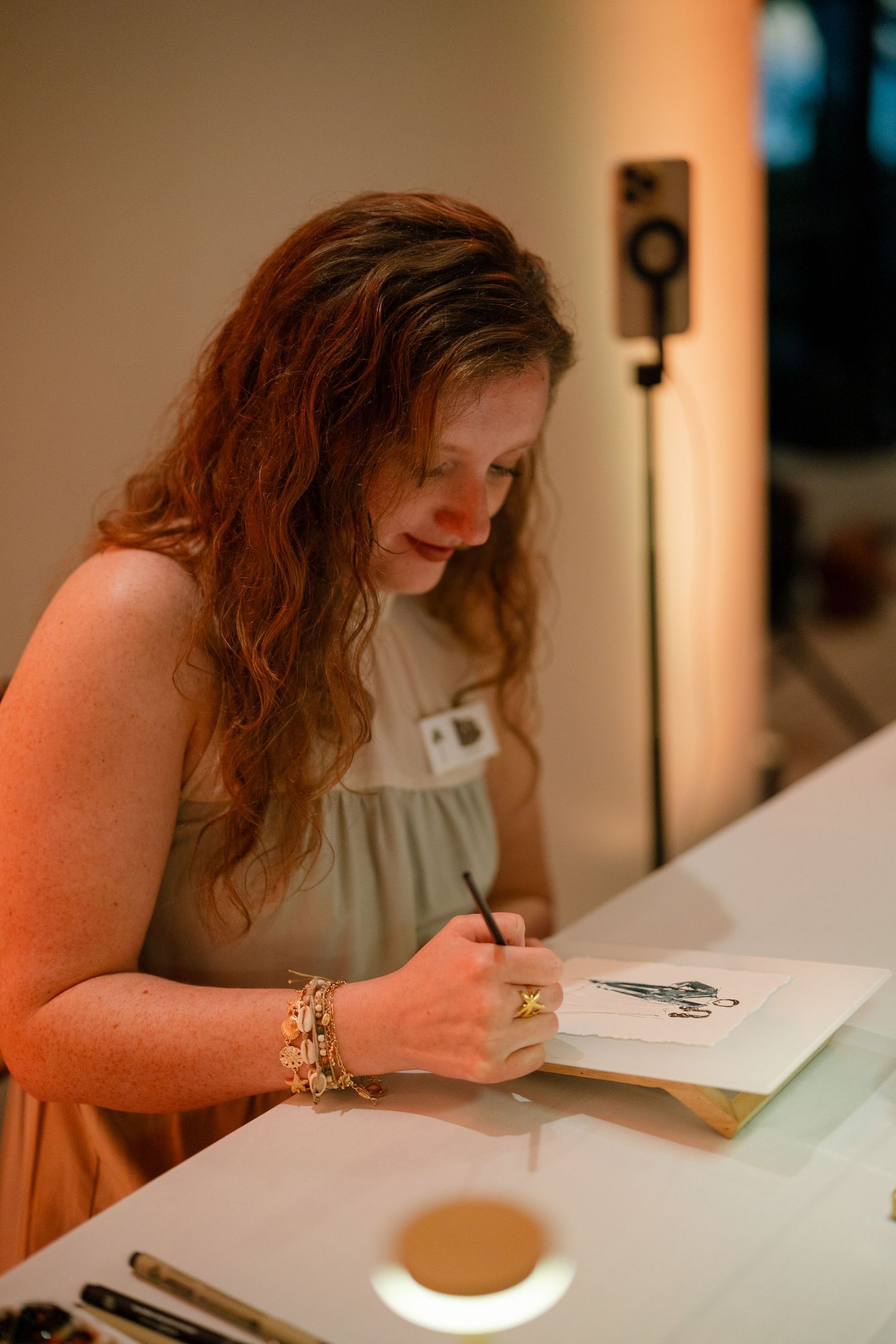 Artist working at illuminated desk in warm lighting conditions.