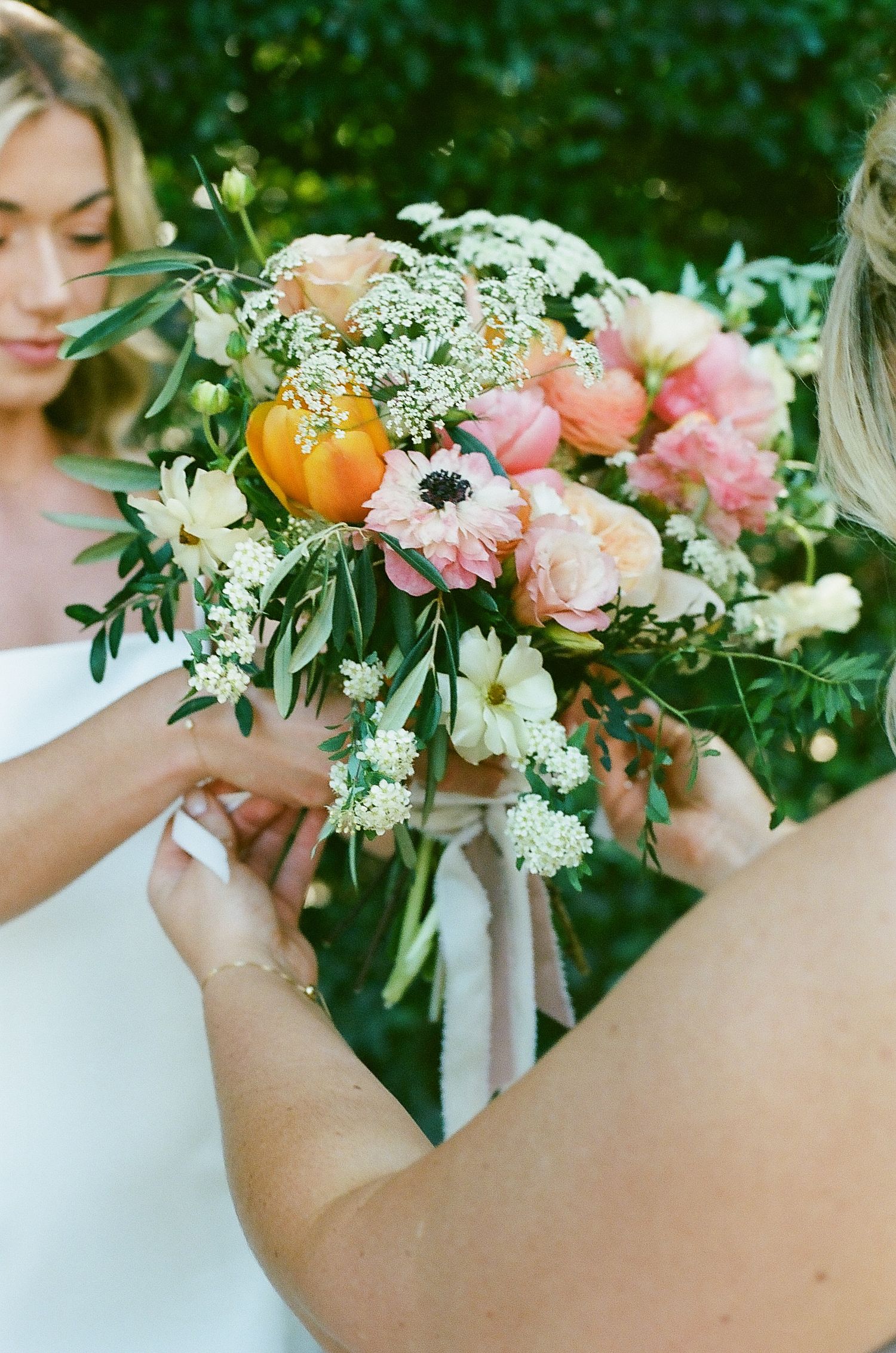 A beautiful bridal bouquet features coral peonies, orange tulips and delicate white flowers.