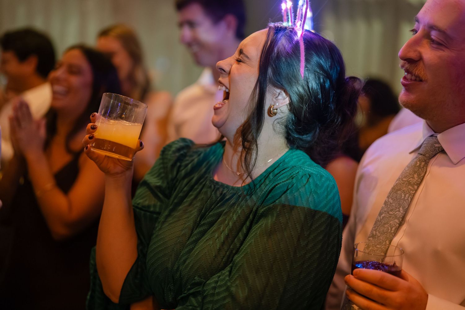 Evening party scene with ambient lighting shows guests enjoying drinks and conversation.
