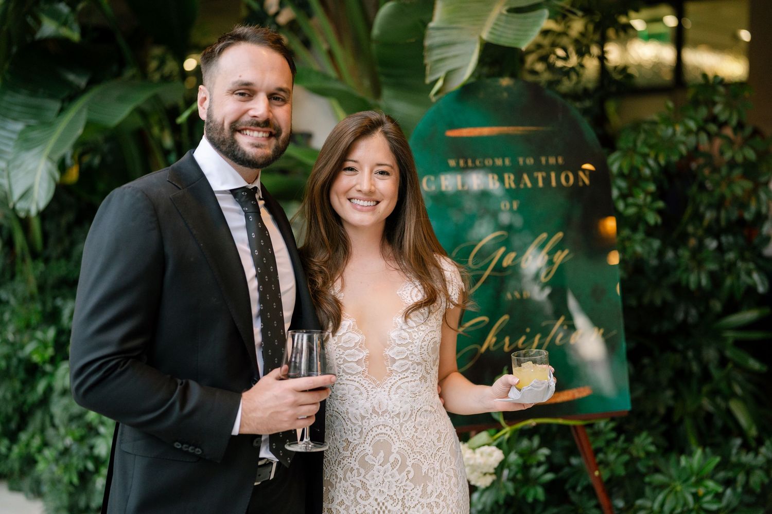 Elegant couple sharing champagne during their wedding reception in a garden setting.