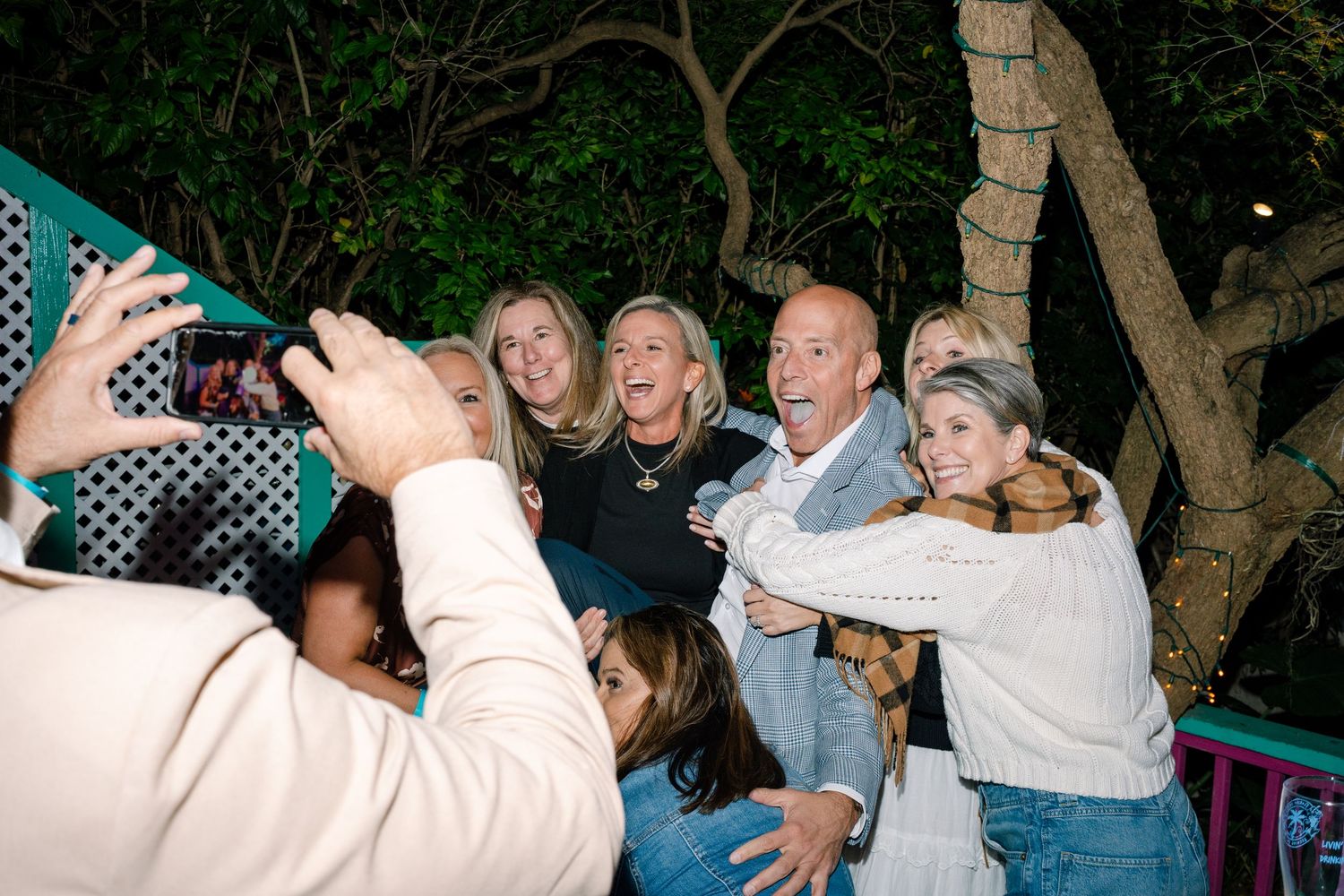 Group of people celebrating outdoors at night with raised arms and joyful expressions.