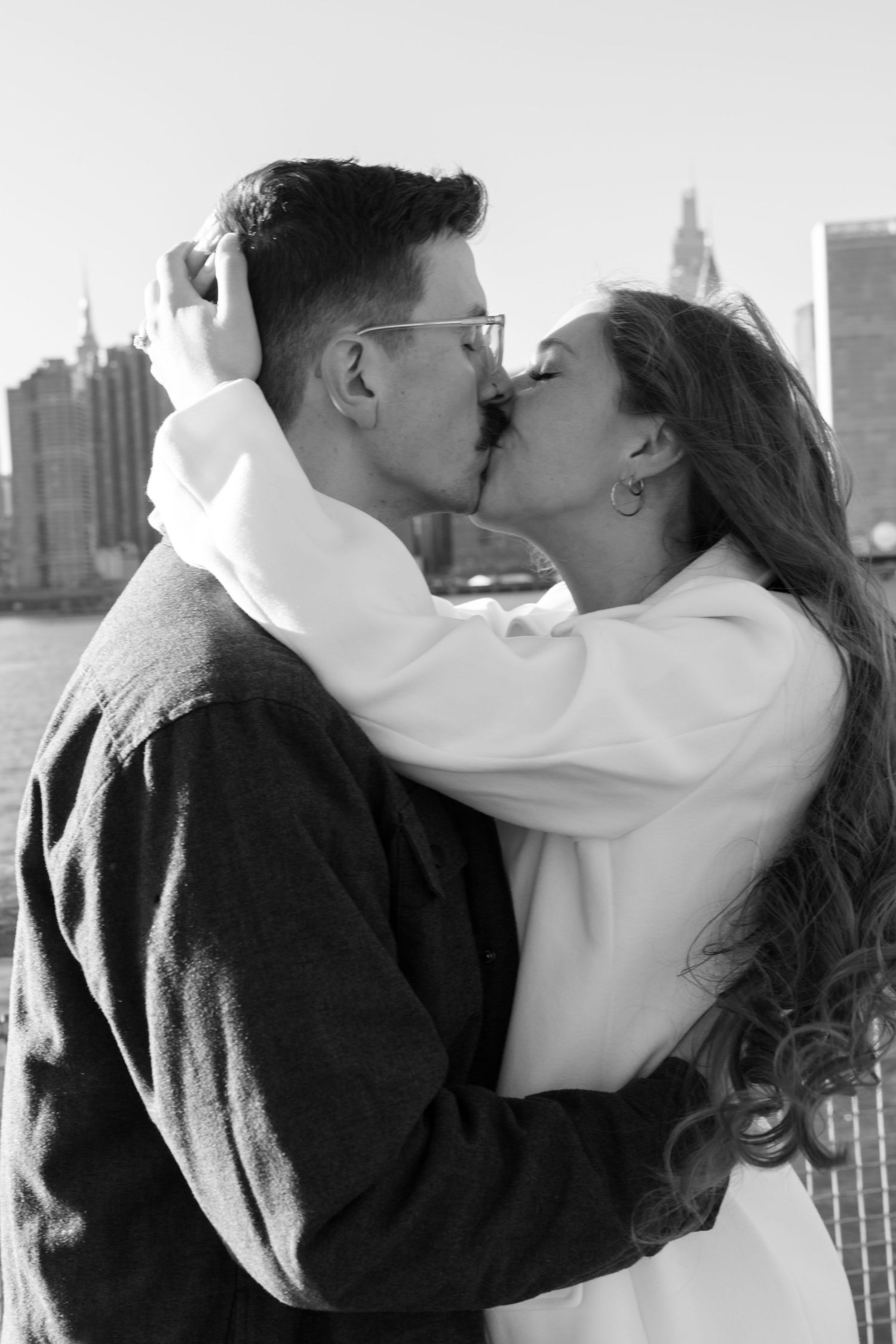 A romantic black and white photo series showing a couple kissing with a city skyline in the background.