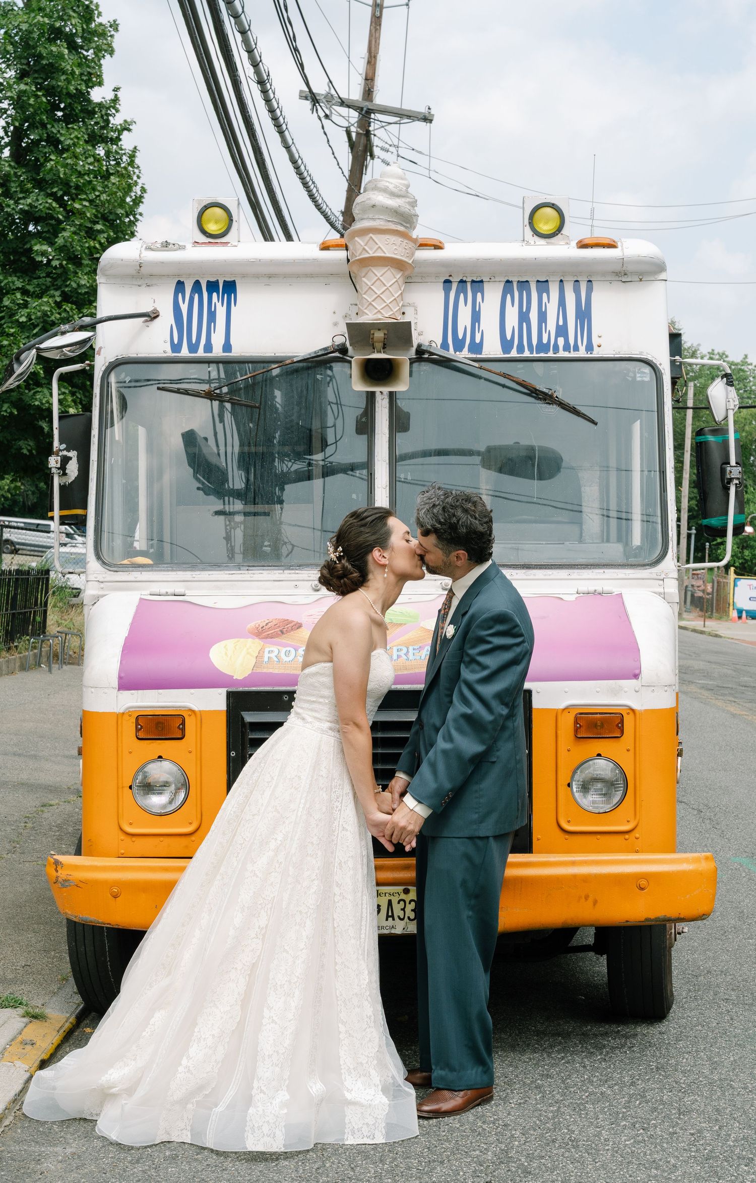 Wedding couple sharing romantic moments in front of vintage ice cream truck.