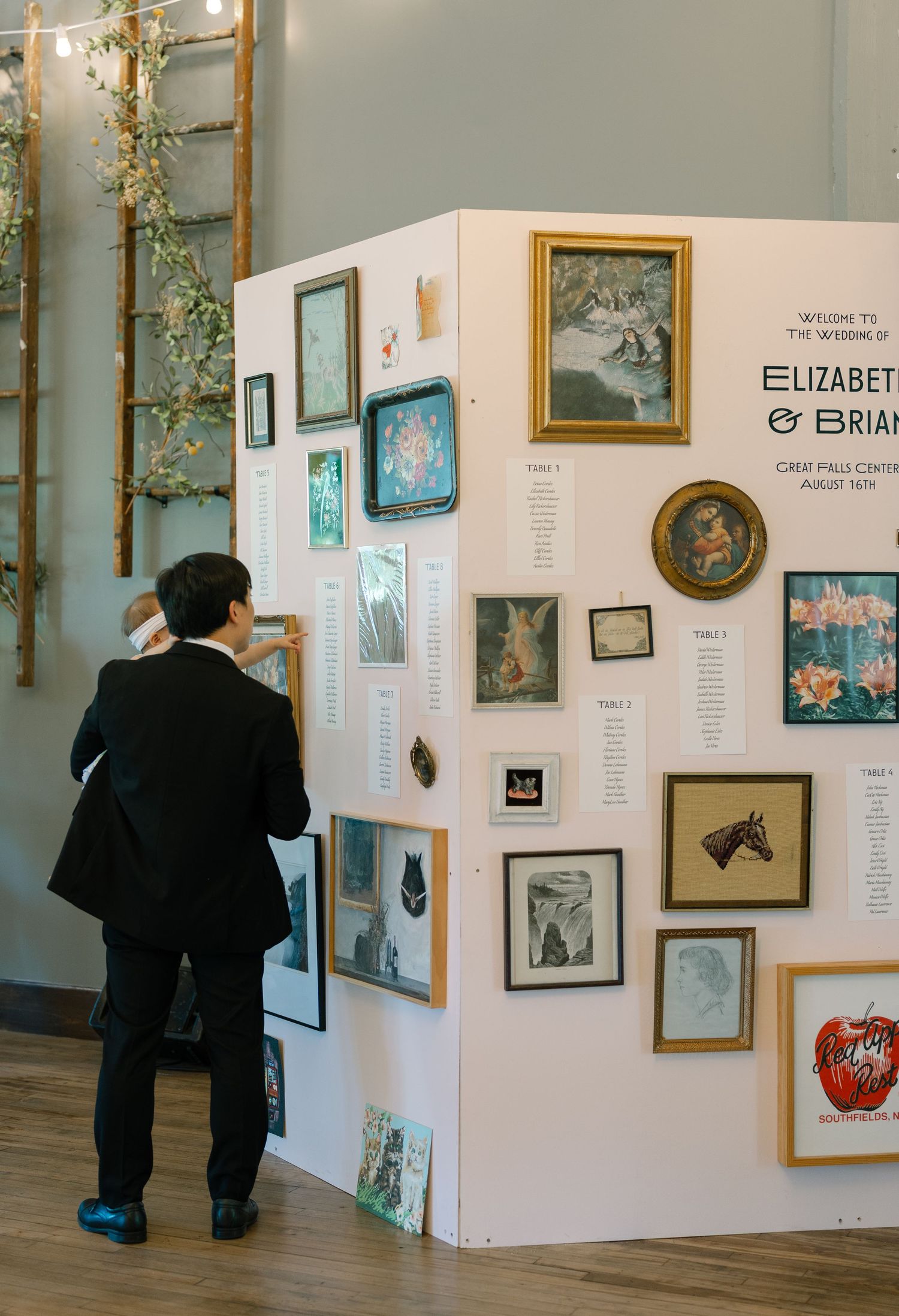 An art gallery installation with white display panels showing framed artwork and decorative elements.