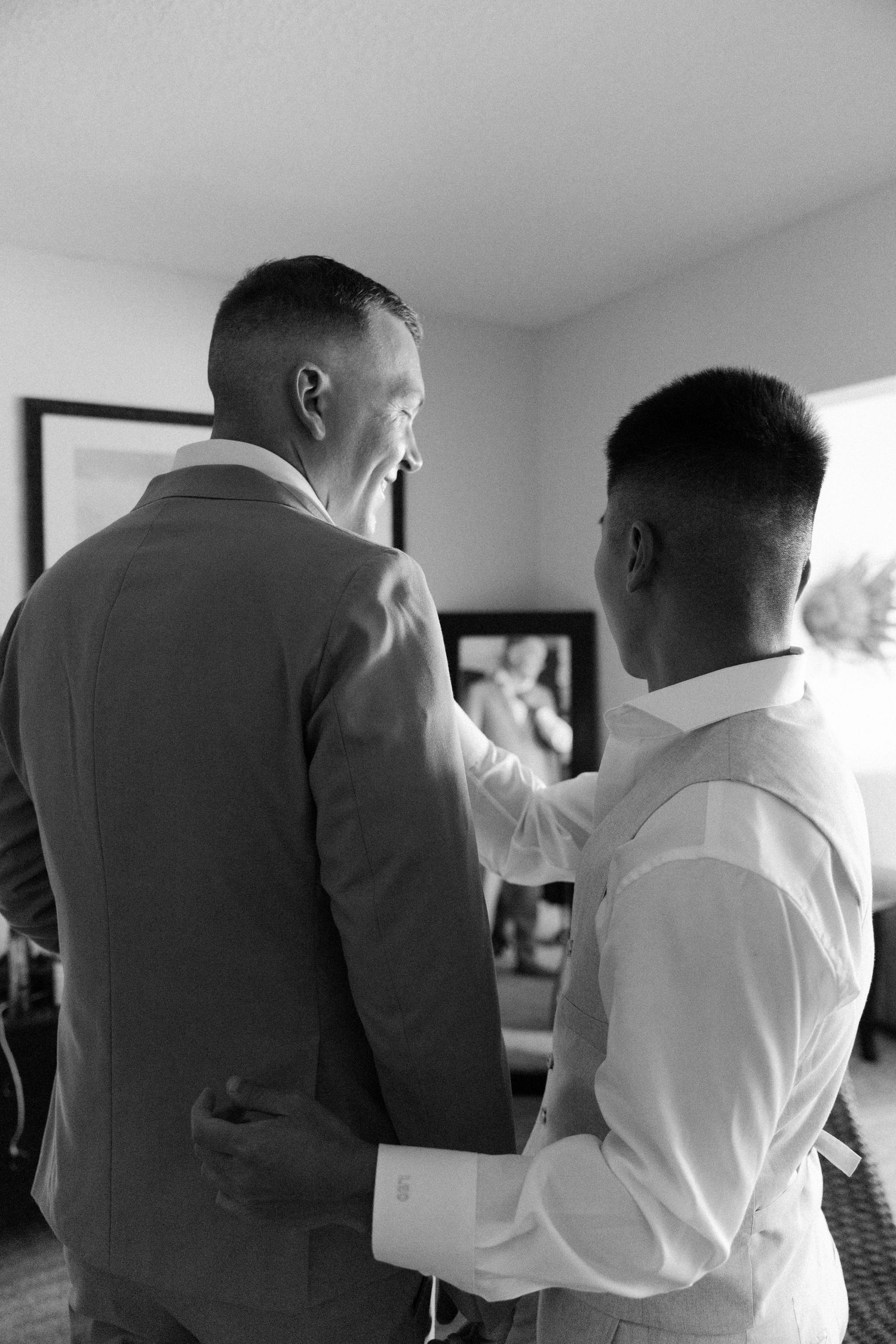 Black and white photo showing people in formal attire preparing for an event indoors.