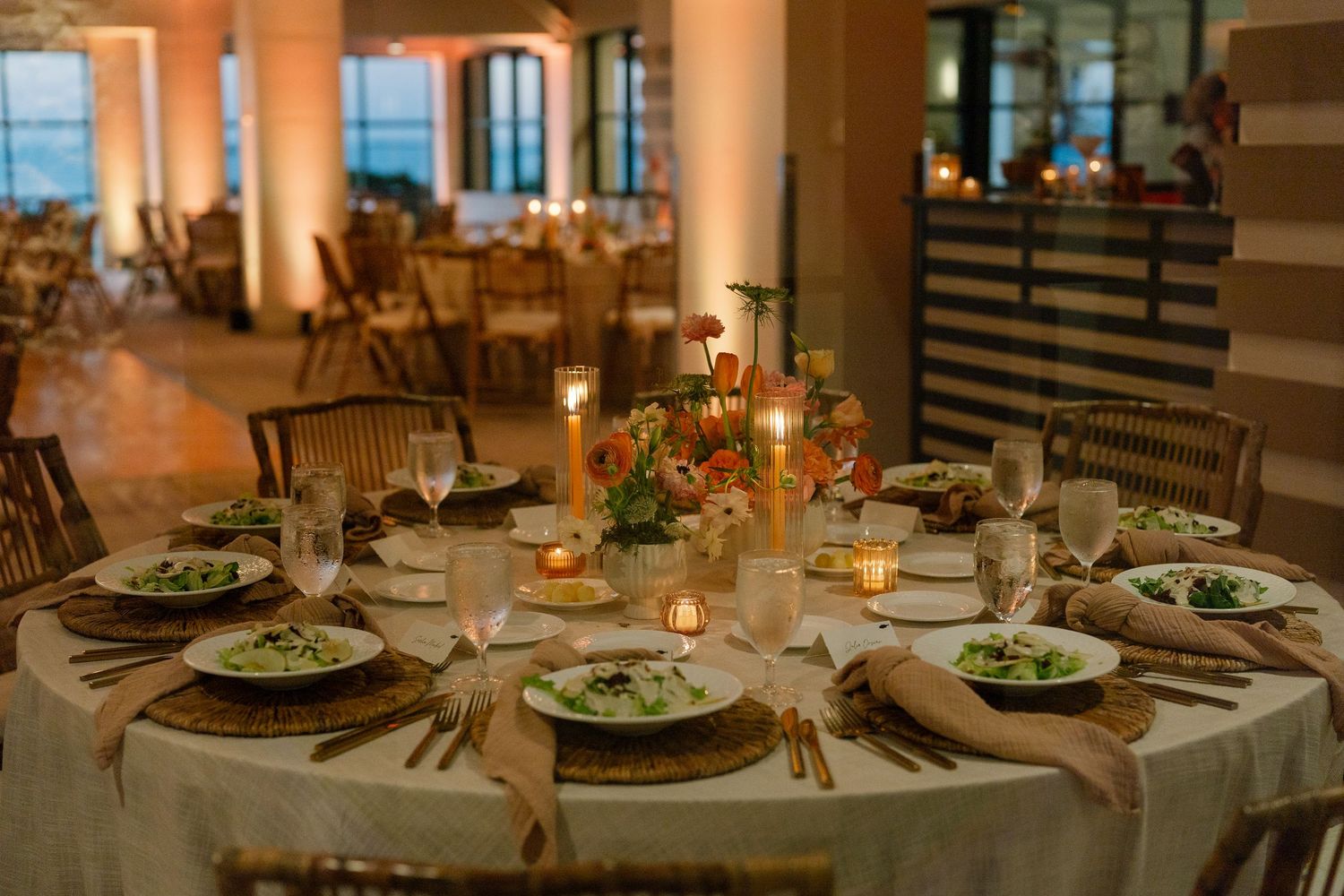 Elegant wedding reception tables set with glowing candlelight and place settings.