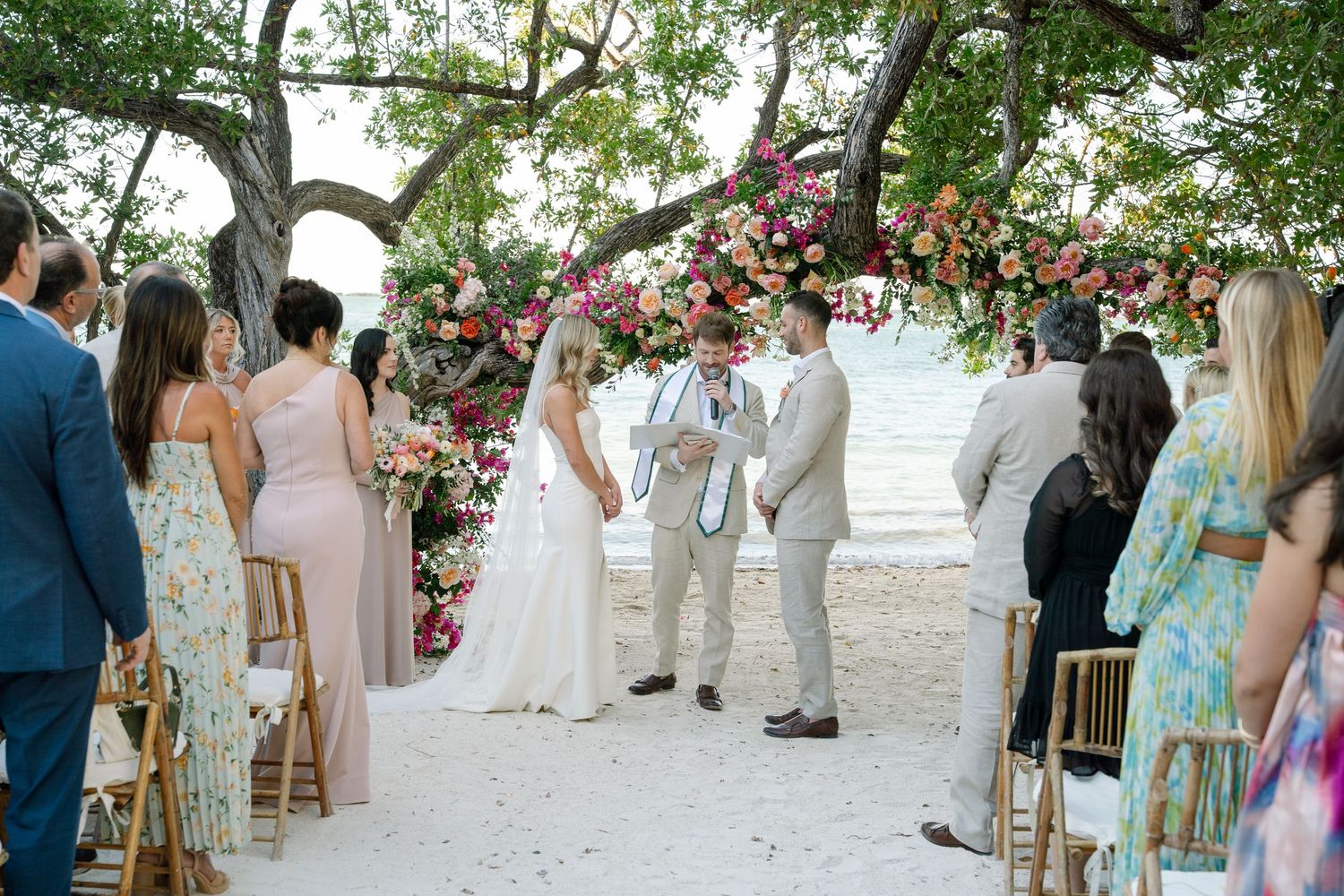 Outdoor beach wedding ceremony setup with wooden chairs and floral decorations.