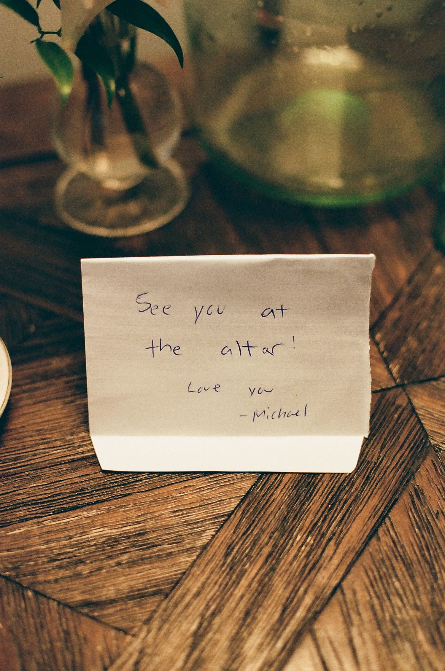 Handwritten romantic notes reading 'See you at the altar' and 'Love you' displayed on wooden table with soft lighting.