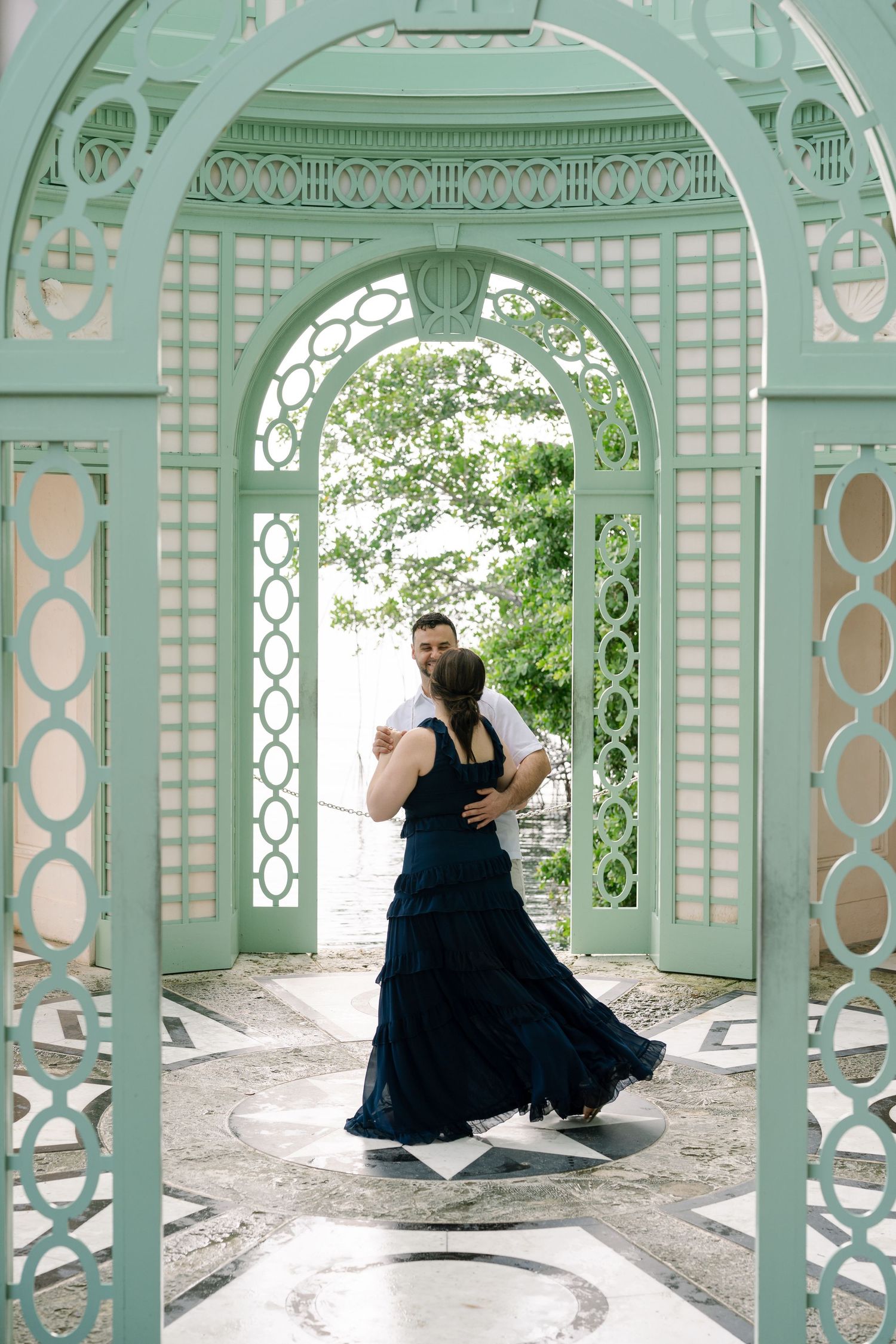 A couple dancing under an ornate mint green archway with lattice details and decorative metalwork.