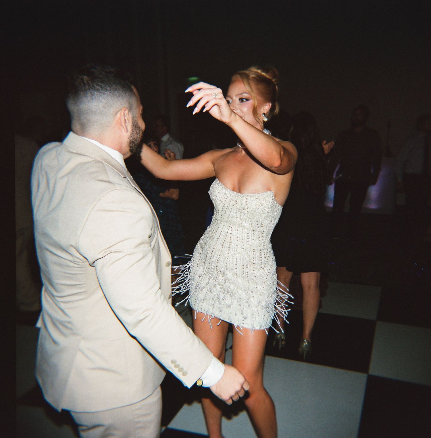 A couple dancing together at a wedding reception, with the bride wearing a white strapless dress.