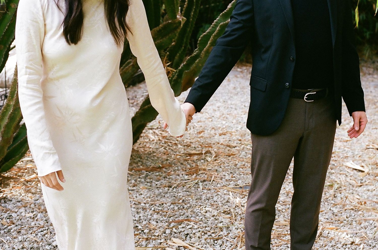 People in formal attire walking together on a gravel path during an outdoor event.