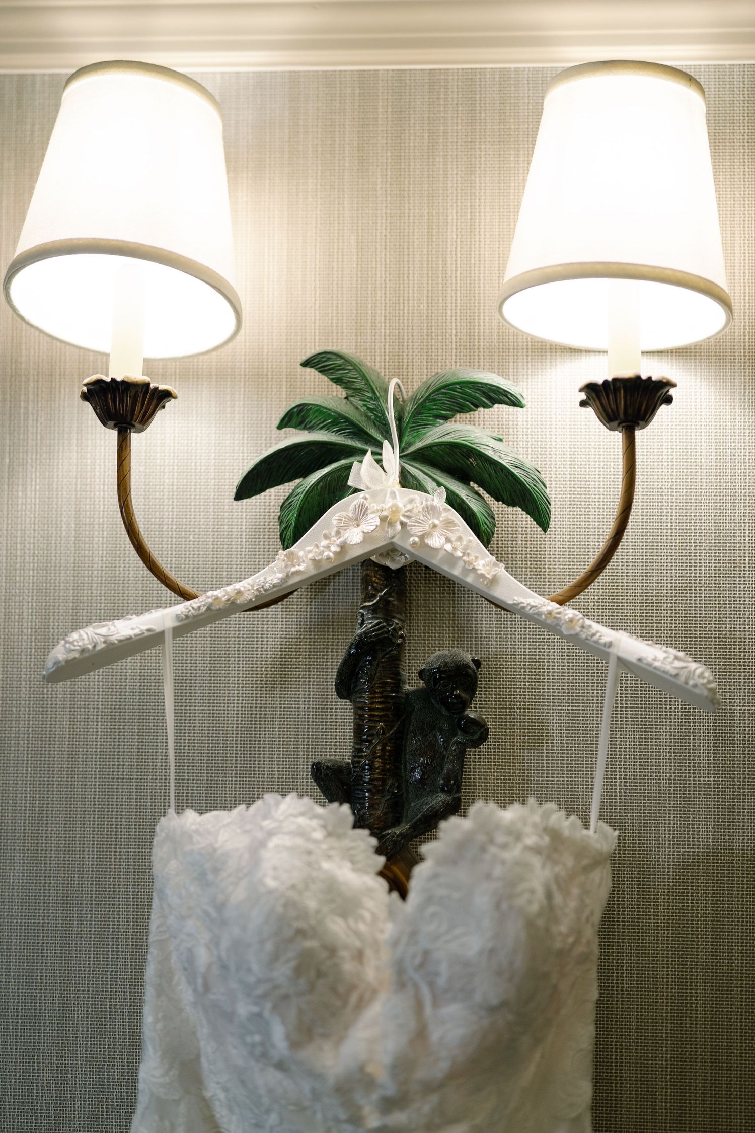 A decorative wall light fixture with palm leaf accents and white lampshades.