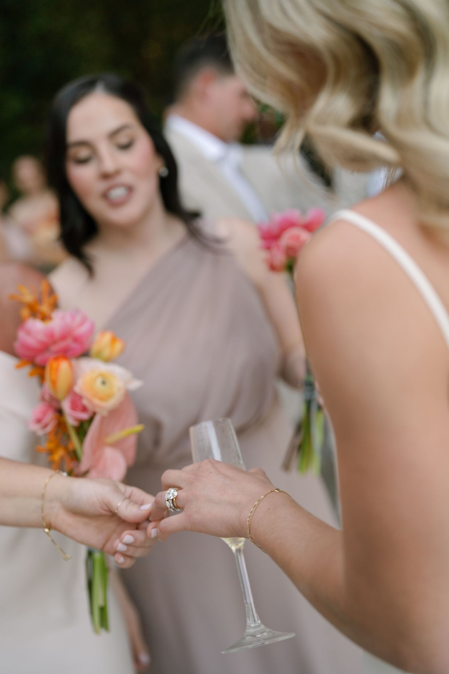 Wedding party members in beige dresses holding champagne glasses during celebrations.