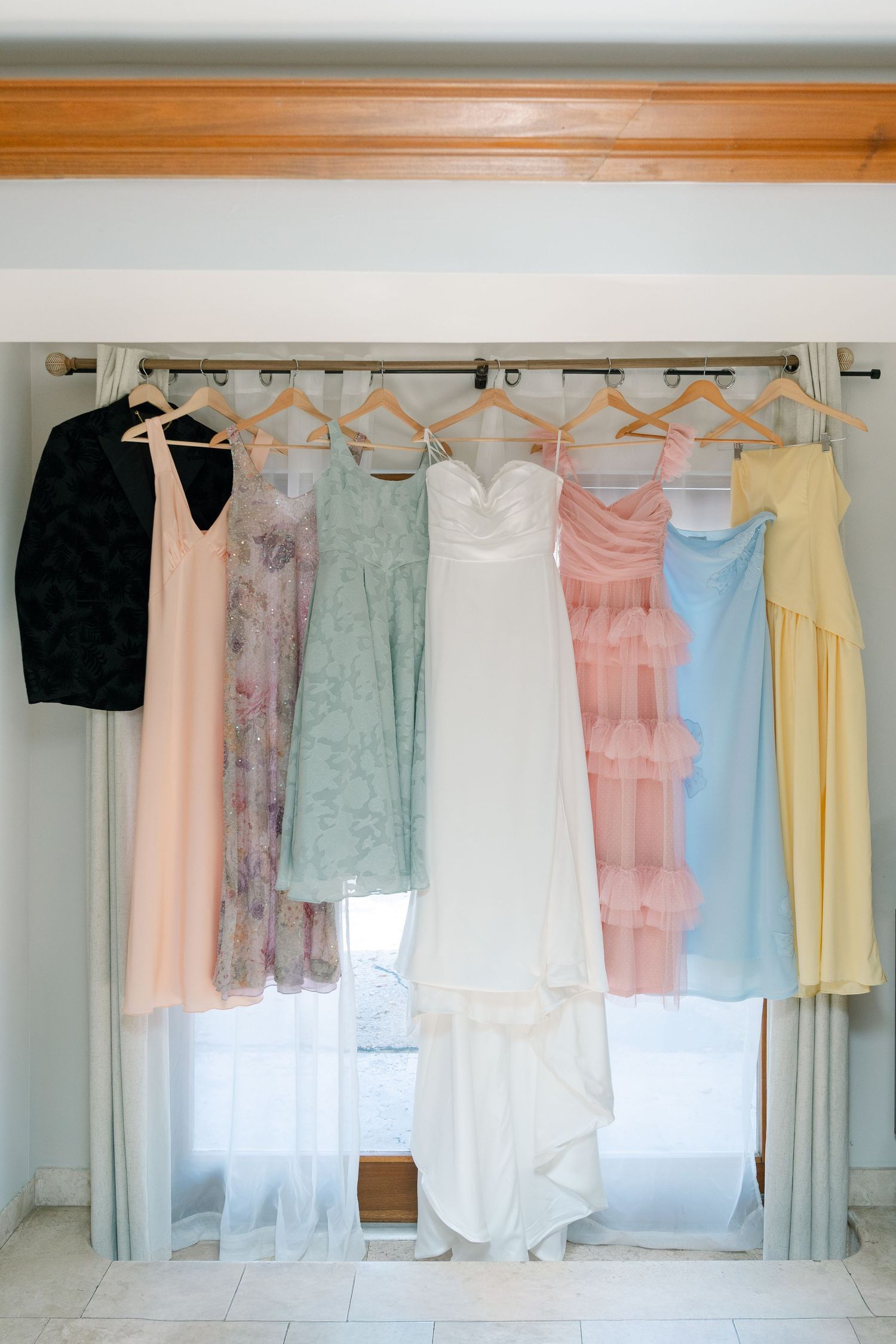 A variety of pastel-colored dresses and clothing items hanging on a clothing rack.