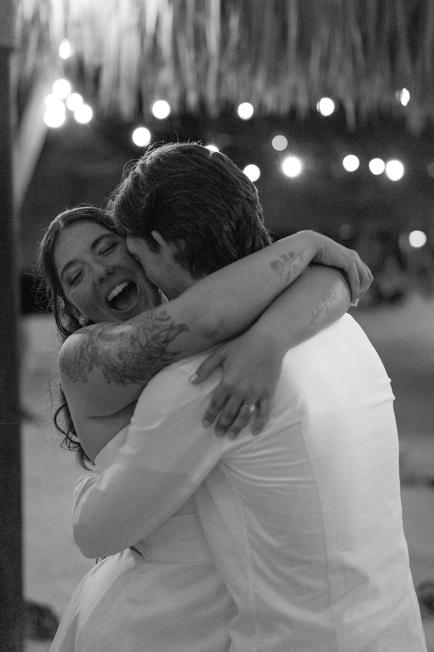 A couple embracing and kissing passionately in a romantic setting with twinkling lights.