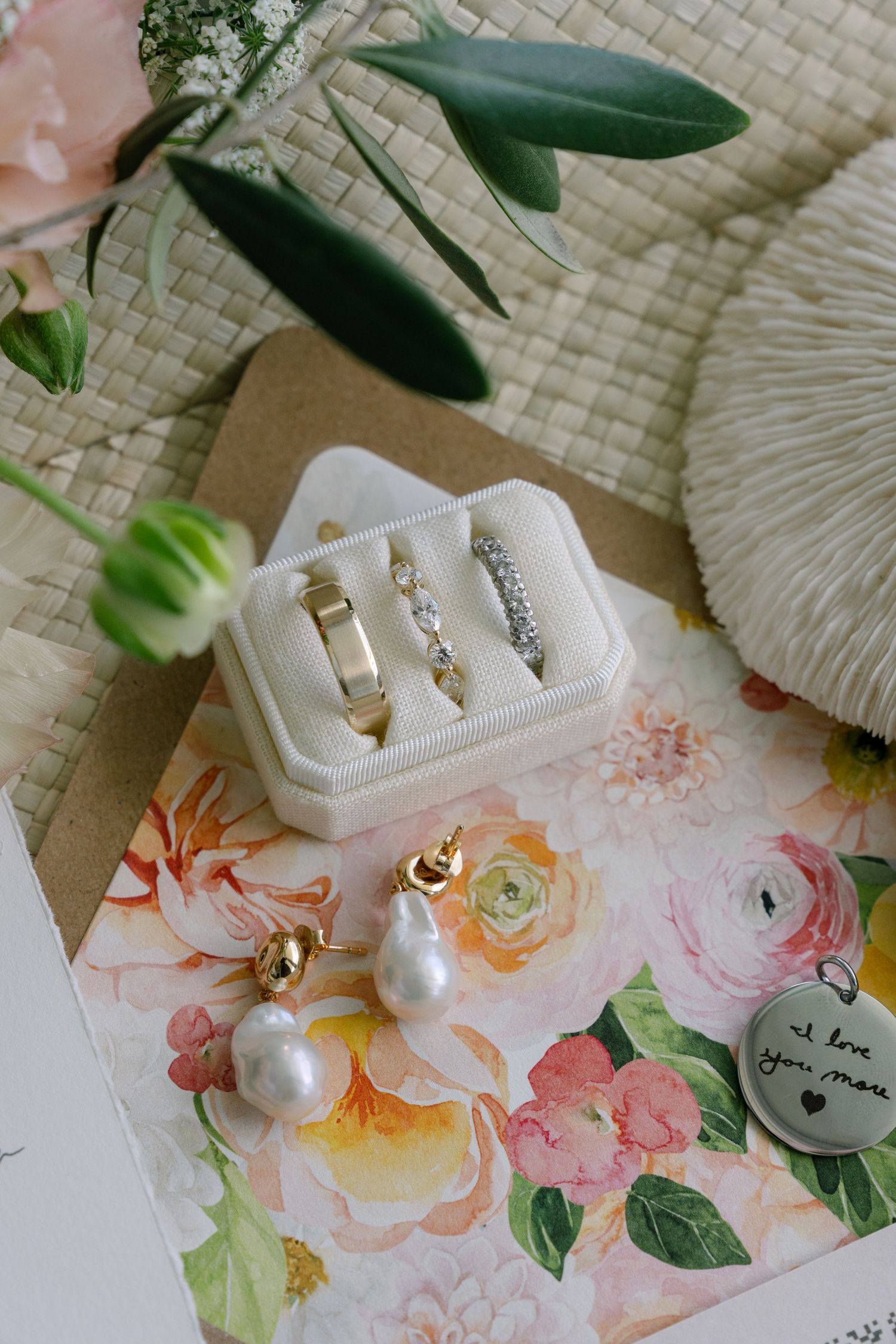Delicate pearl earrings and jewelry displayed on a floral pattern with green leaves in soft lighting.