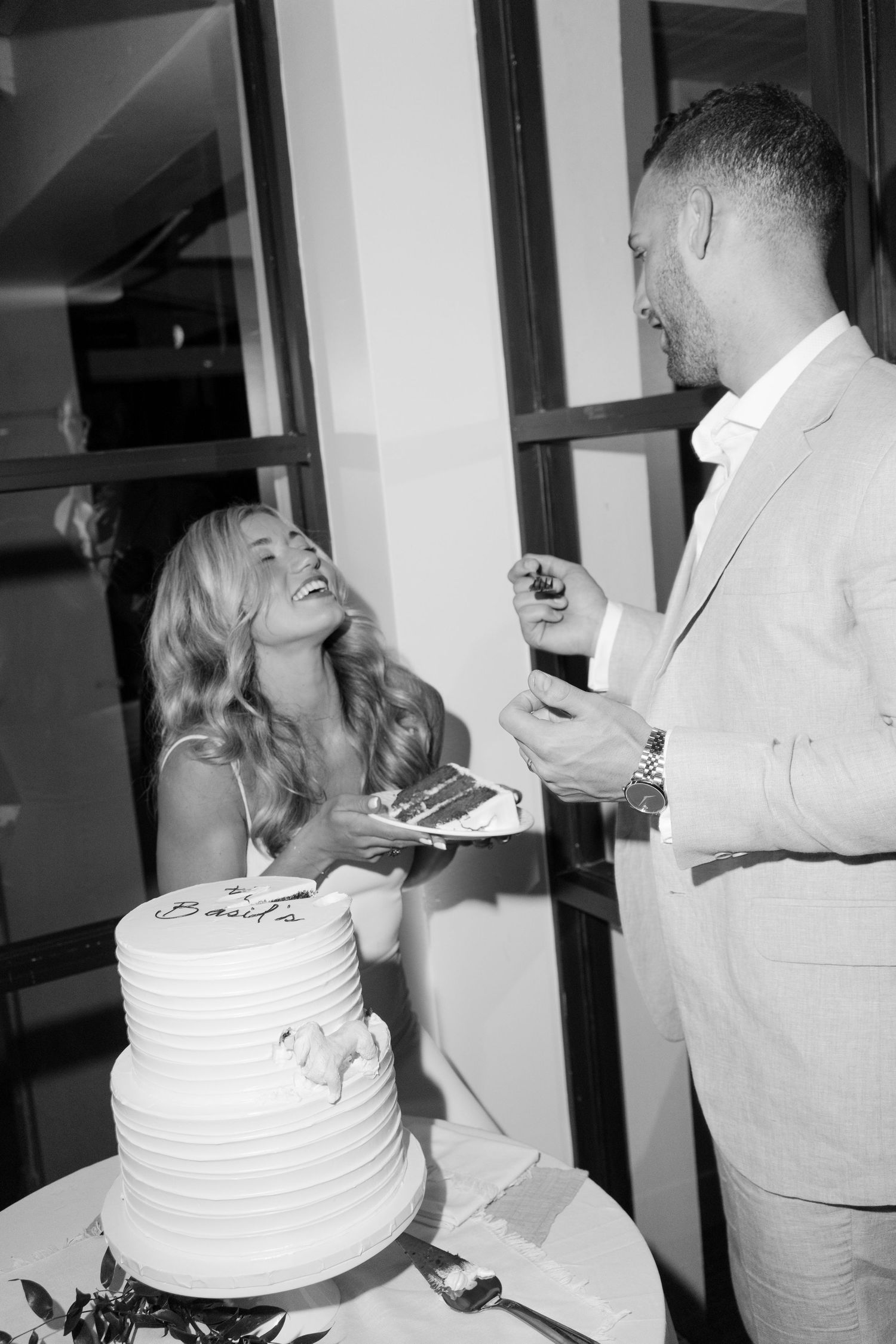 Black and white photo of wedding cake cutting ceremony at reception.