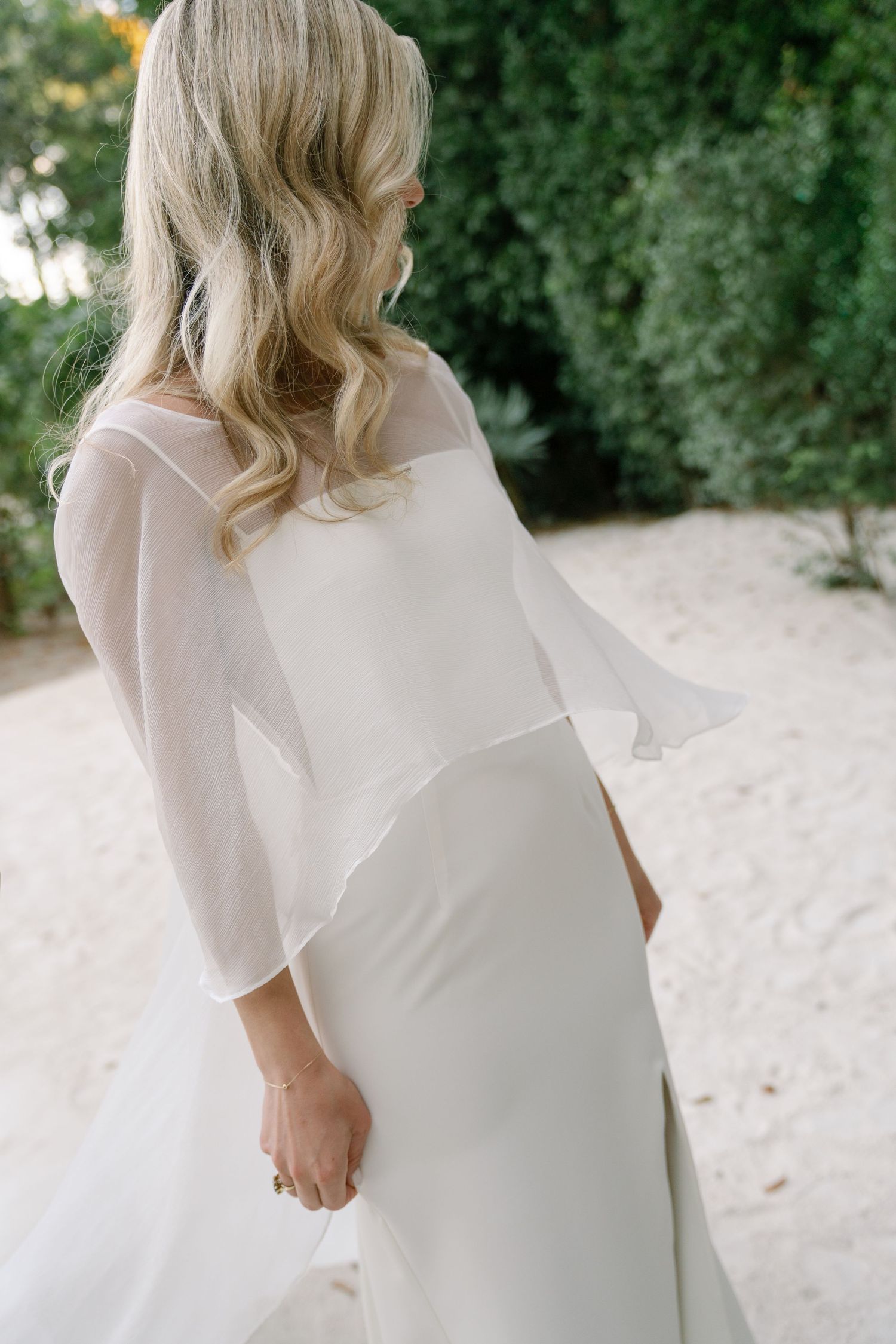 Close-up details of an elegant white wedding dress with flowing fabric and delicate design elements.
