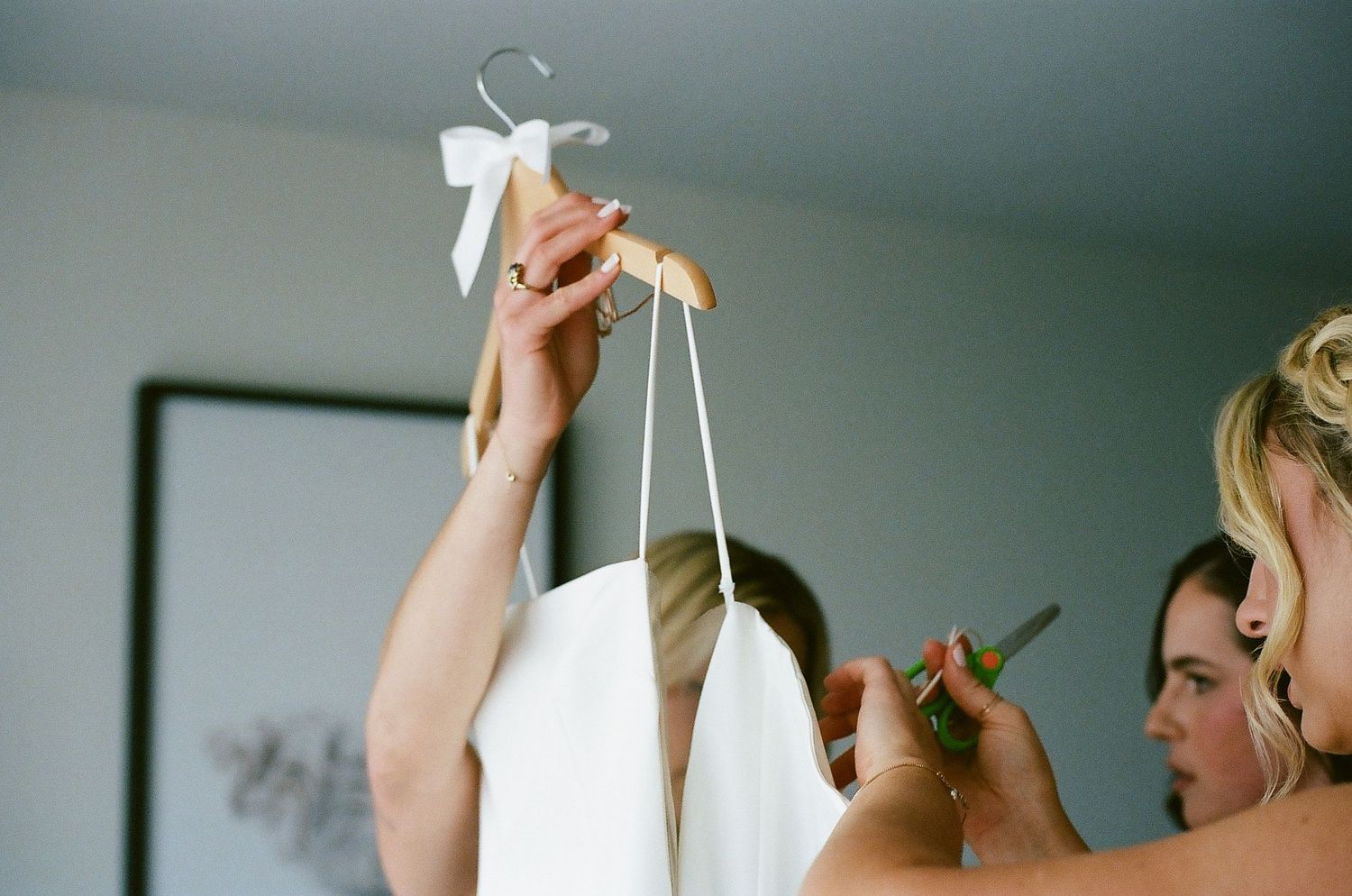 Wedding dress preparation scene with white gown being lifted on hanger.