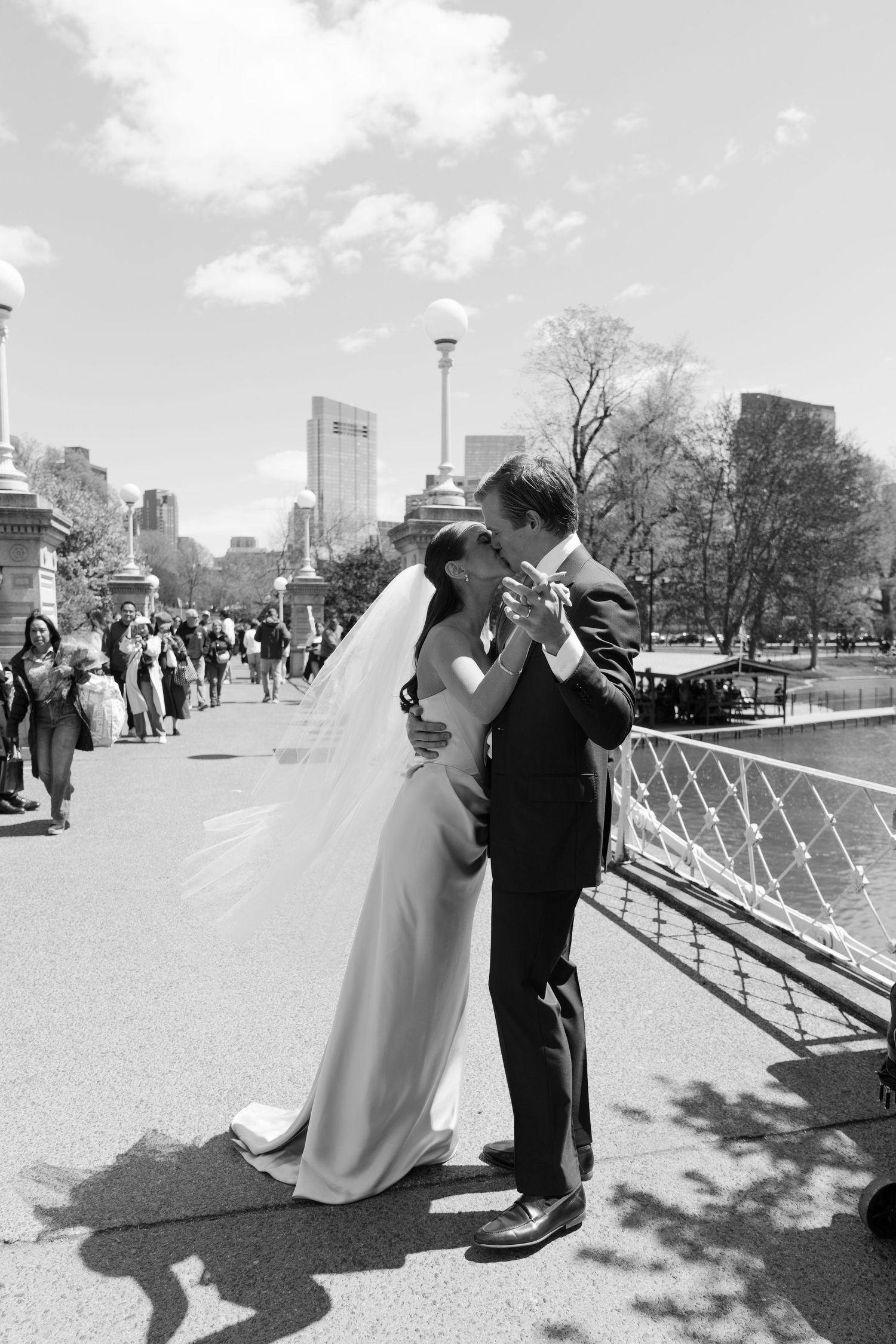 Black and white photo of bride and groom sharing a kiss on a bridge in Boston Public Garden on their wedding day.