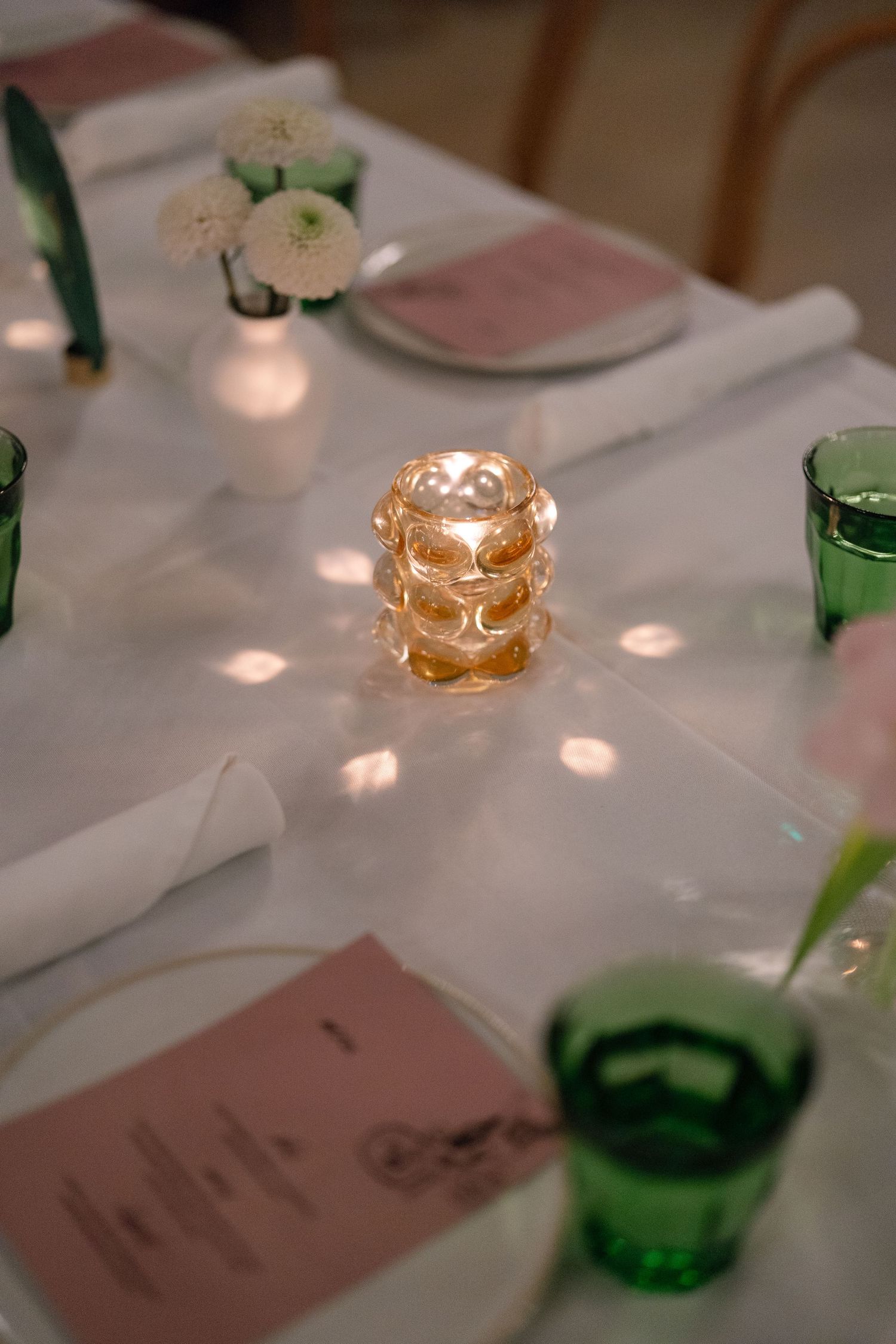 Elegant table setting with soft candlelight and green glassware at a formal dinner event.