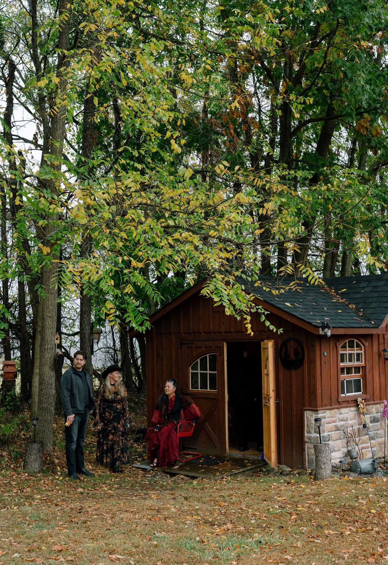 Wooden cabins nestled among autumn trees with fallen leaves on the ground.