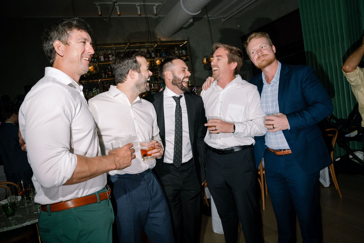 Wedding guests in formal attire mingling and socializing at an evening reception.