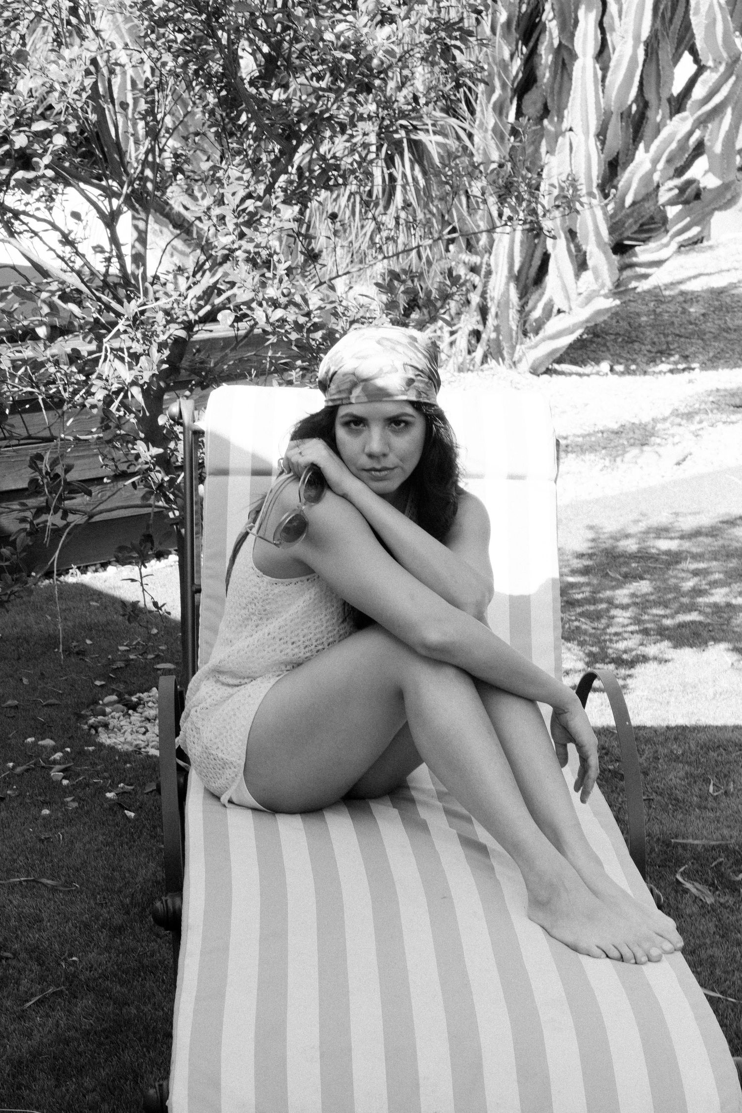 Person lounging on a striped outdoor chair in black and white artistic photos.