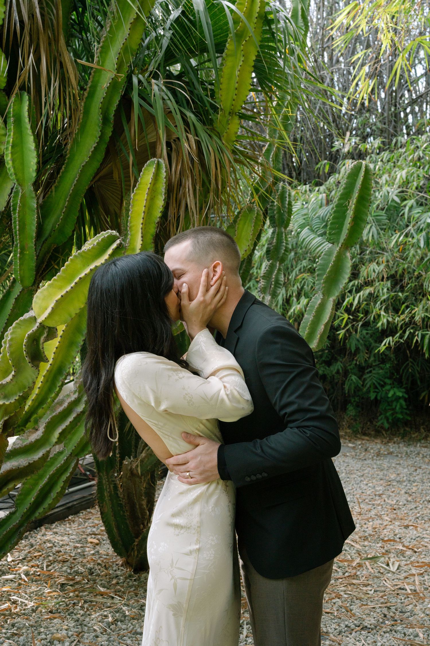 Couple sharing intimate moment among tropical plants and cacti in garden setting.