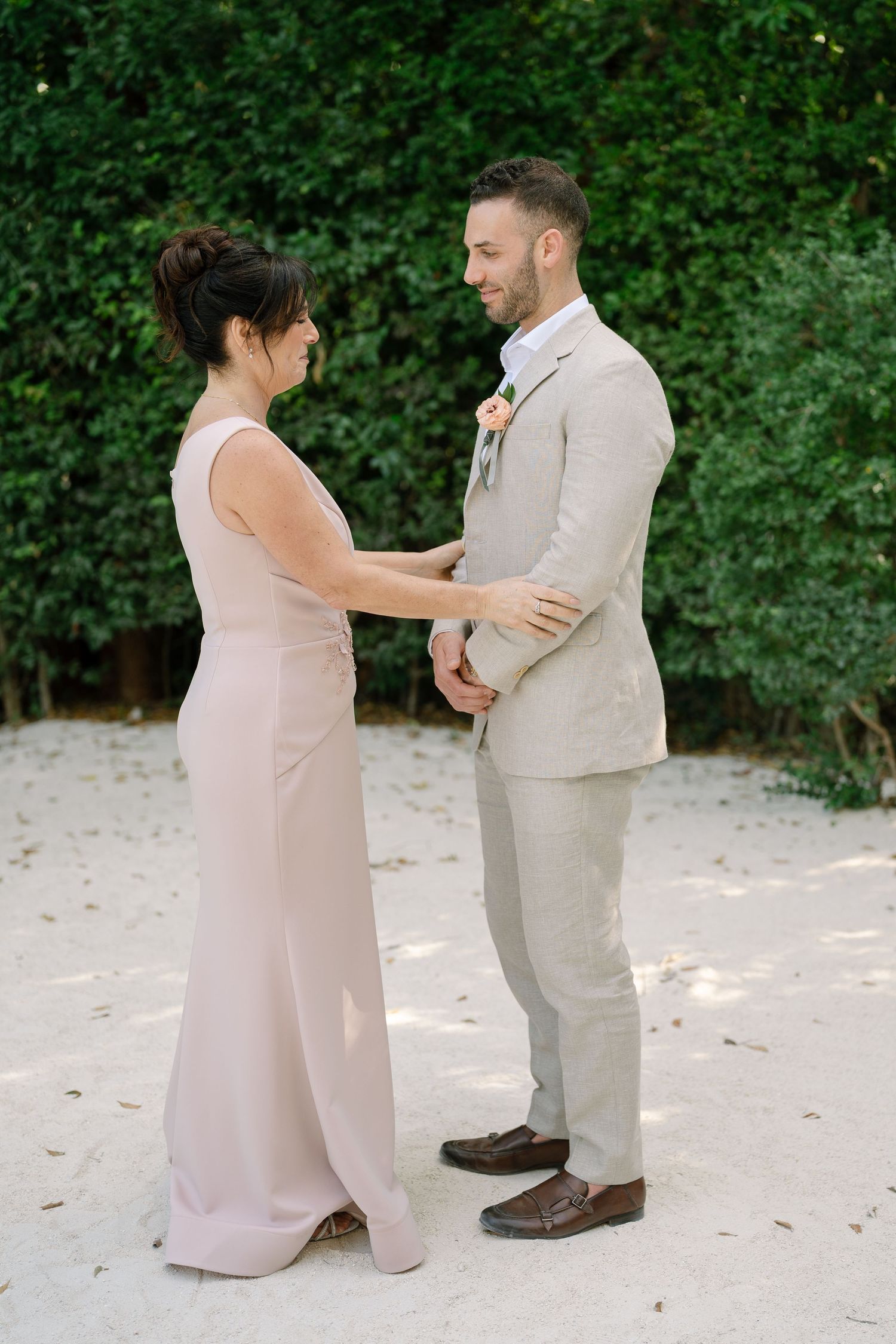 Wedding couple sharing an intimate moment outdoors with greenery backdrop and soft lighting.