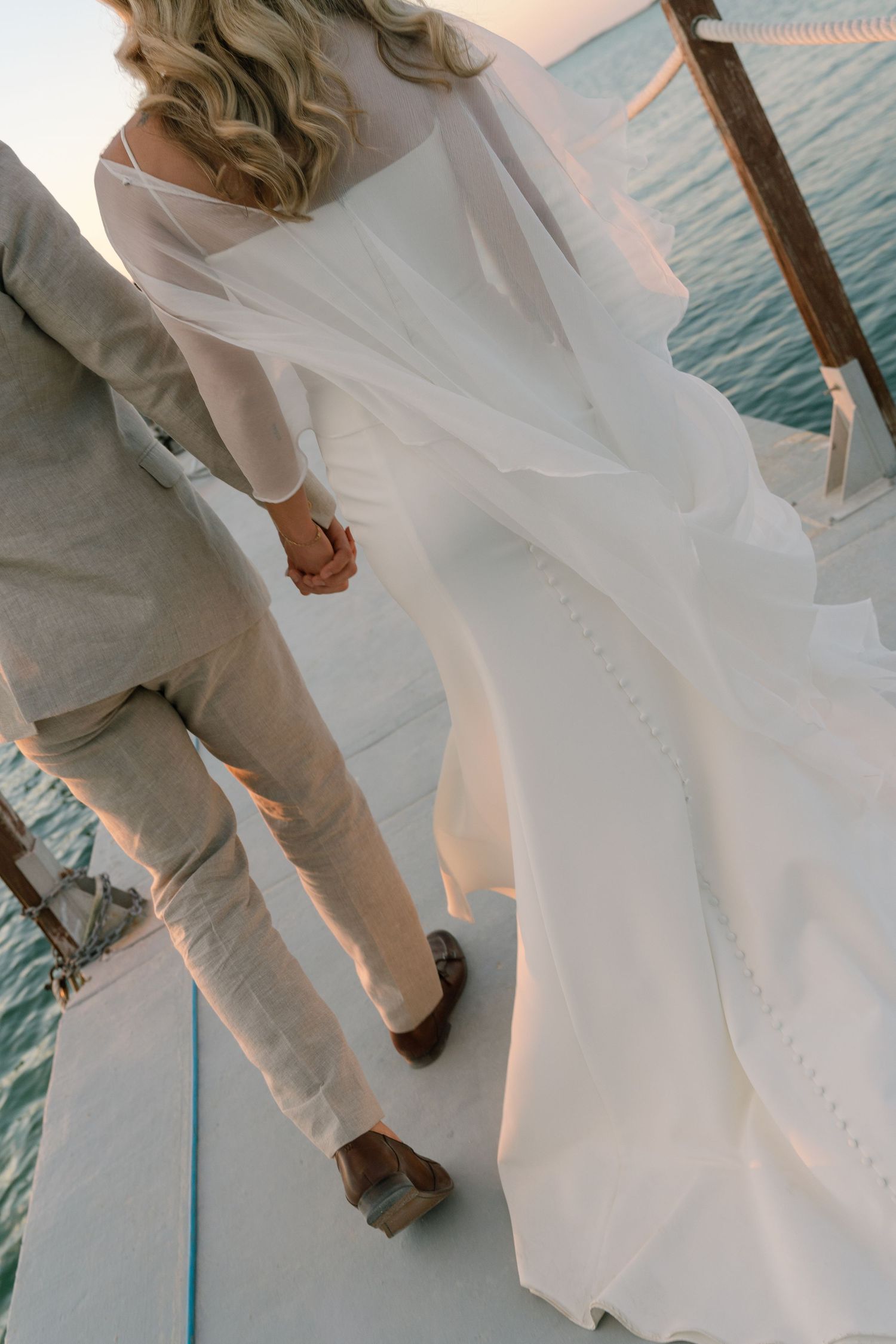White wedding attire flows in the breeze against a stunning oceanfront backdrop.