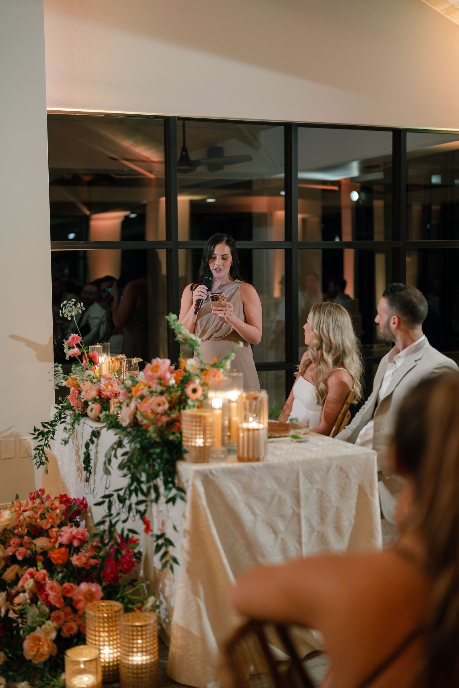Wedding reception dinner setup with elegant floral centerpieces and candlelight.