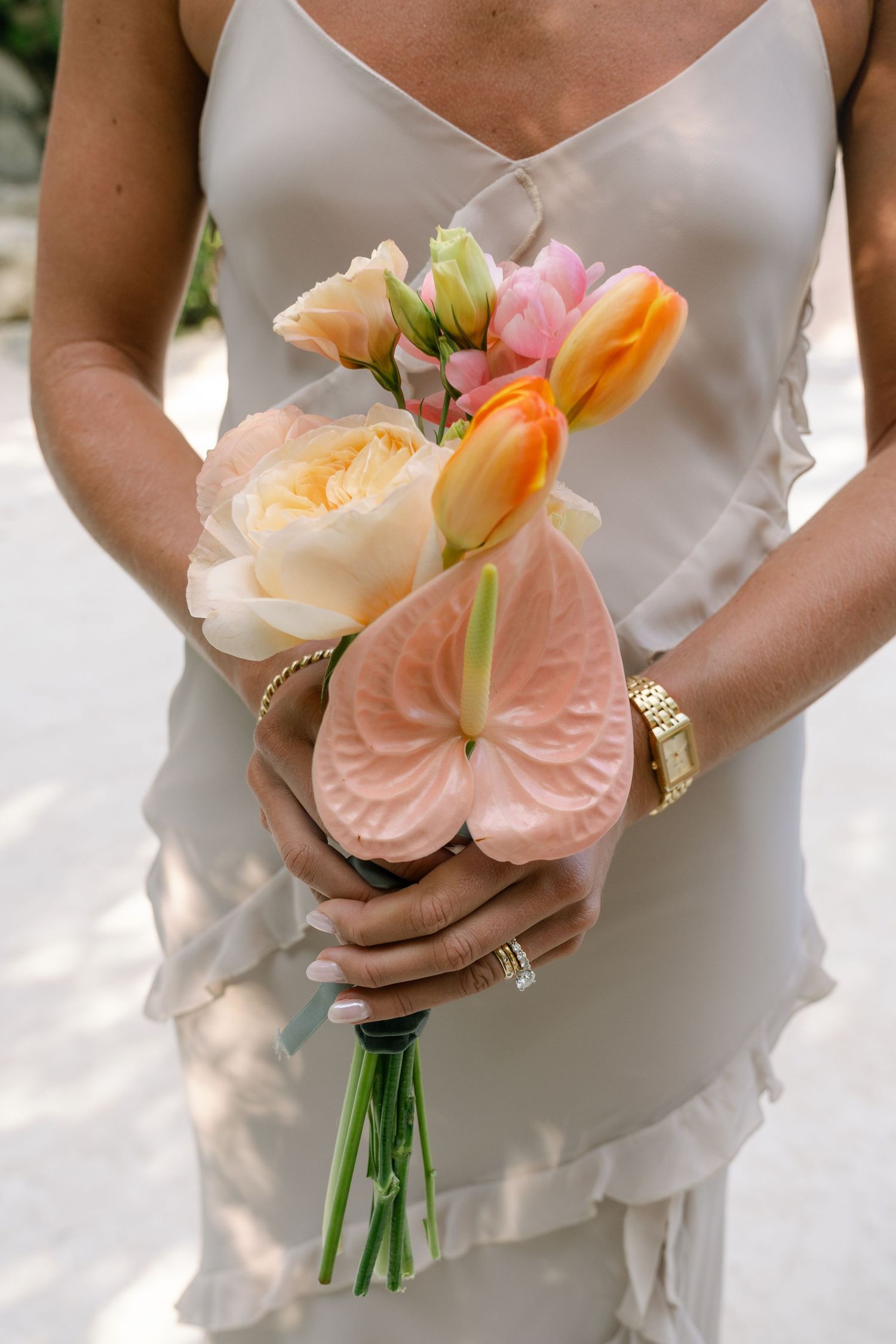 Close-up of peach and coral colored wedding bouquet with anthurium flowers and roses.