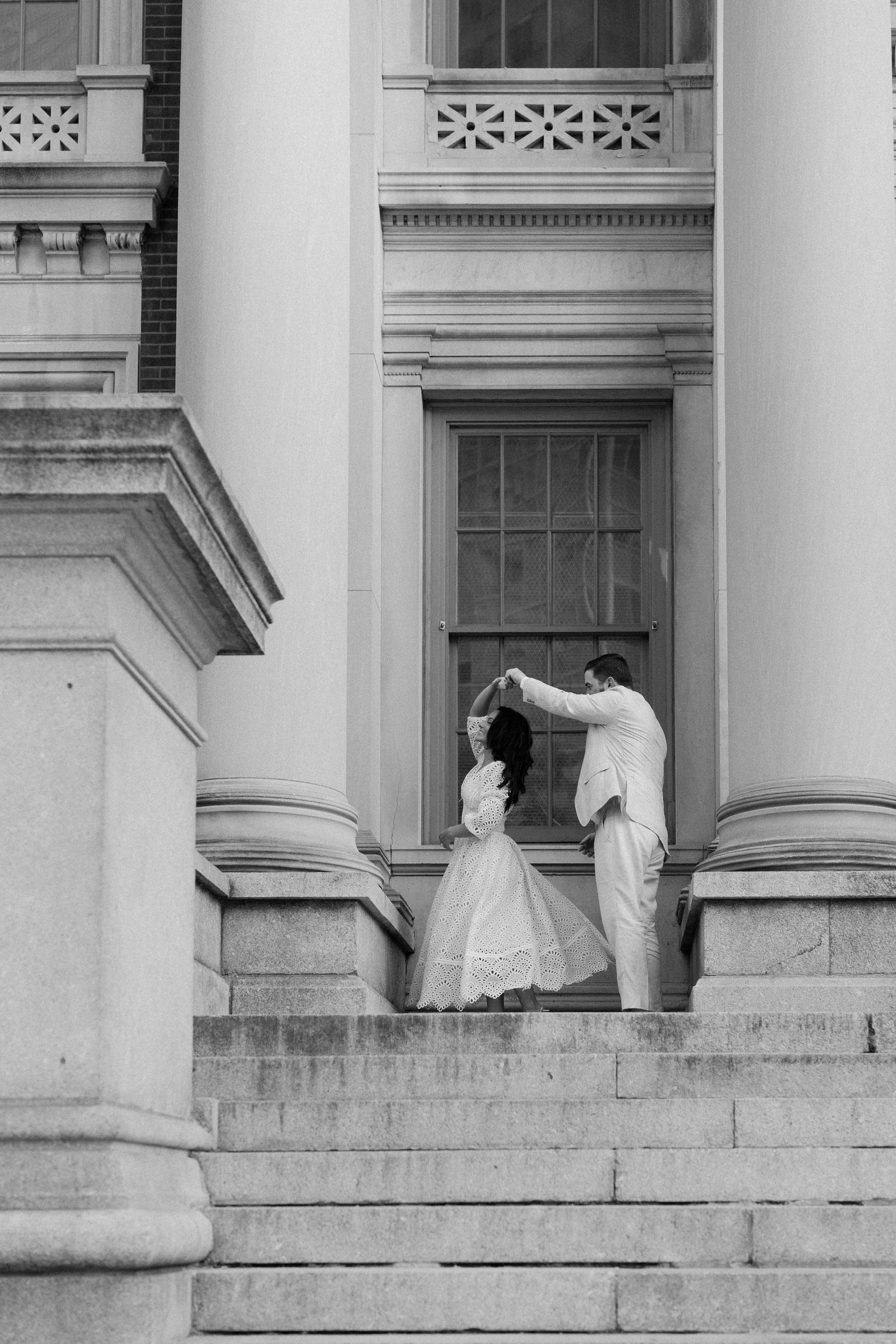 Couple dancing on grand building steps in black and white wedding photo.