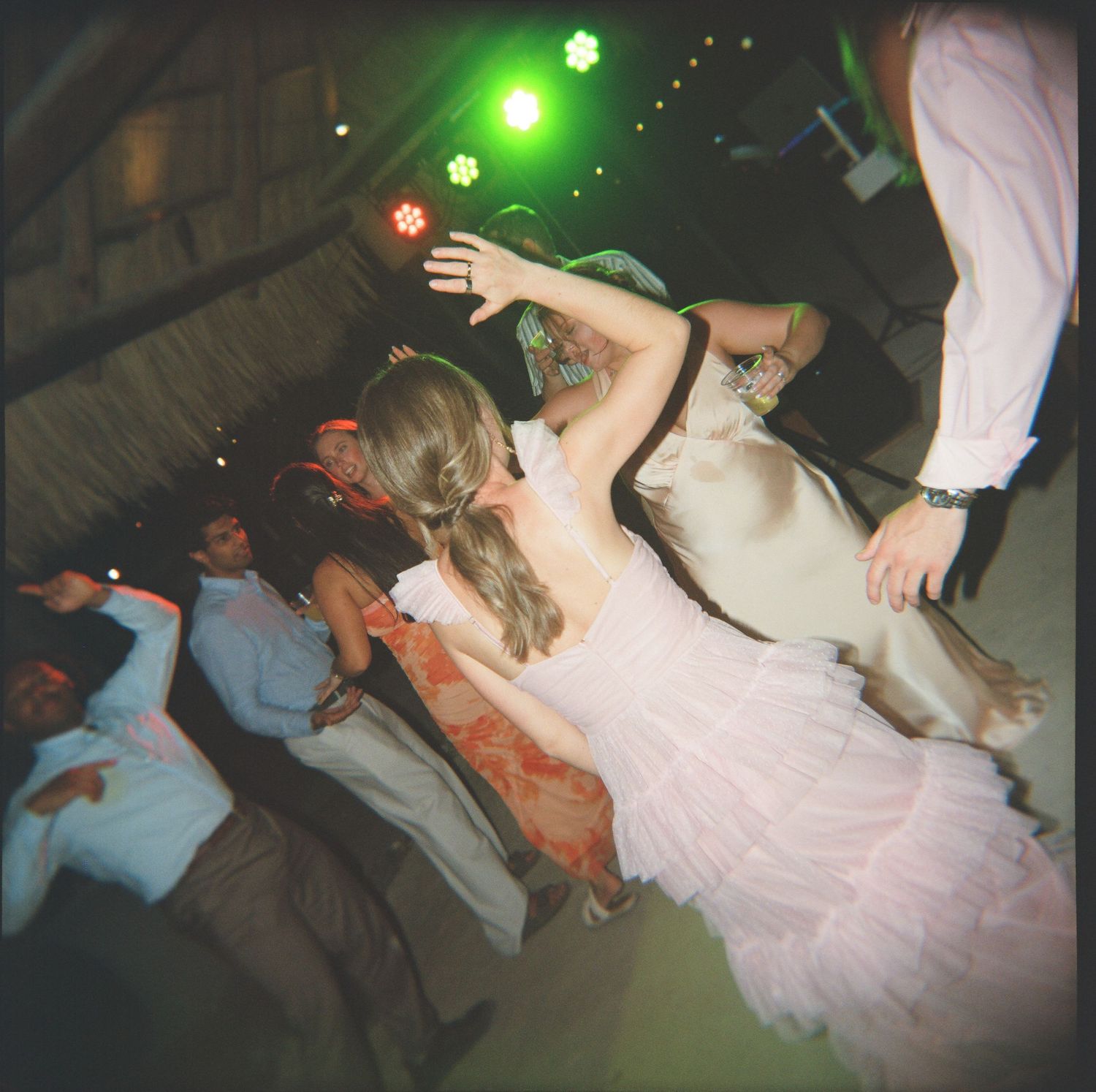 Bride in white gown dancing energetically on the floor at tropical wedding reception.