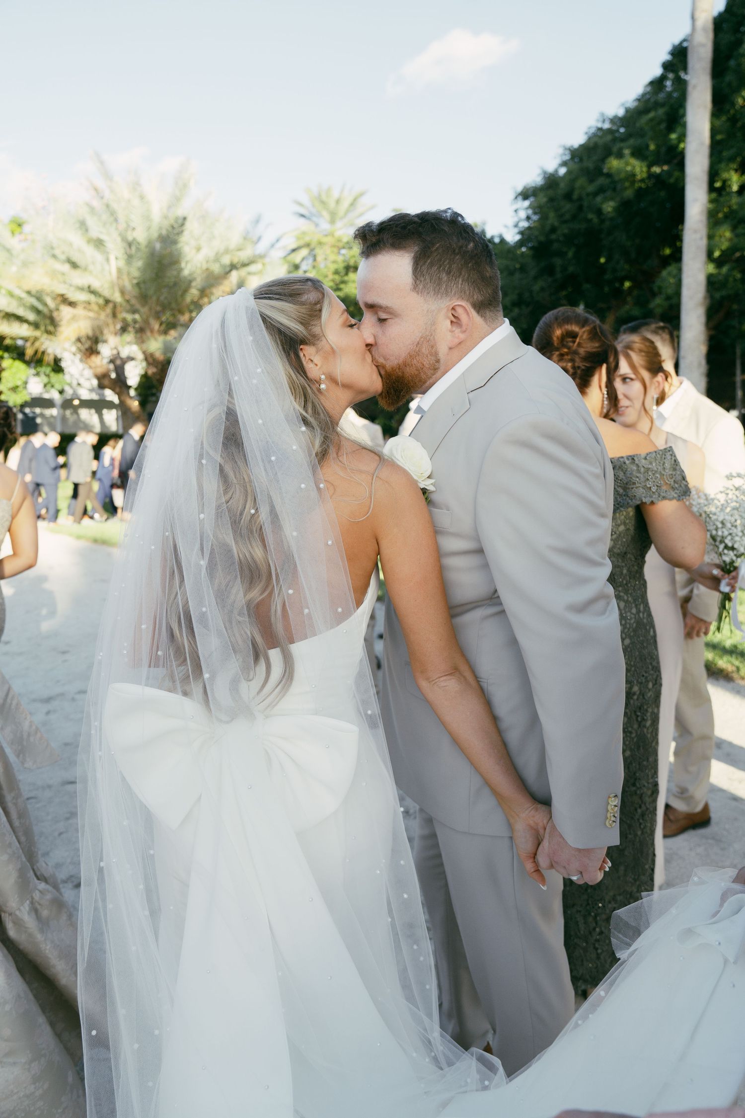 Newlyweds share their first kiss as a married couple during an outdoor garden wedding ceremony.